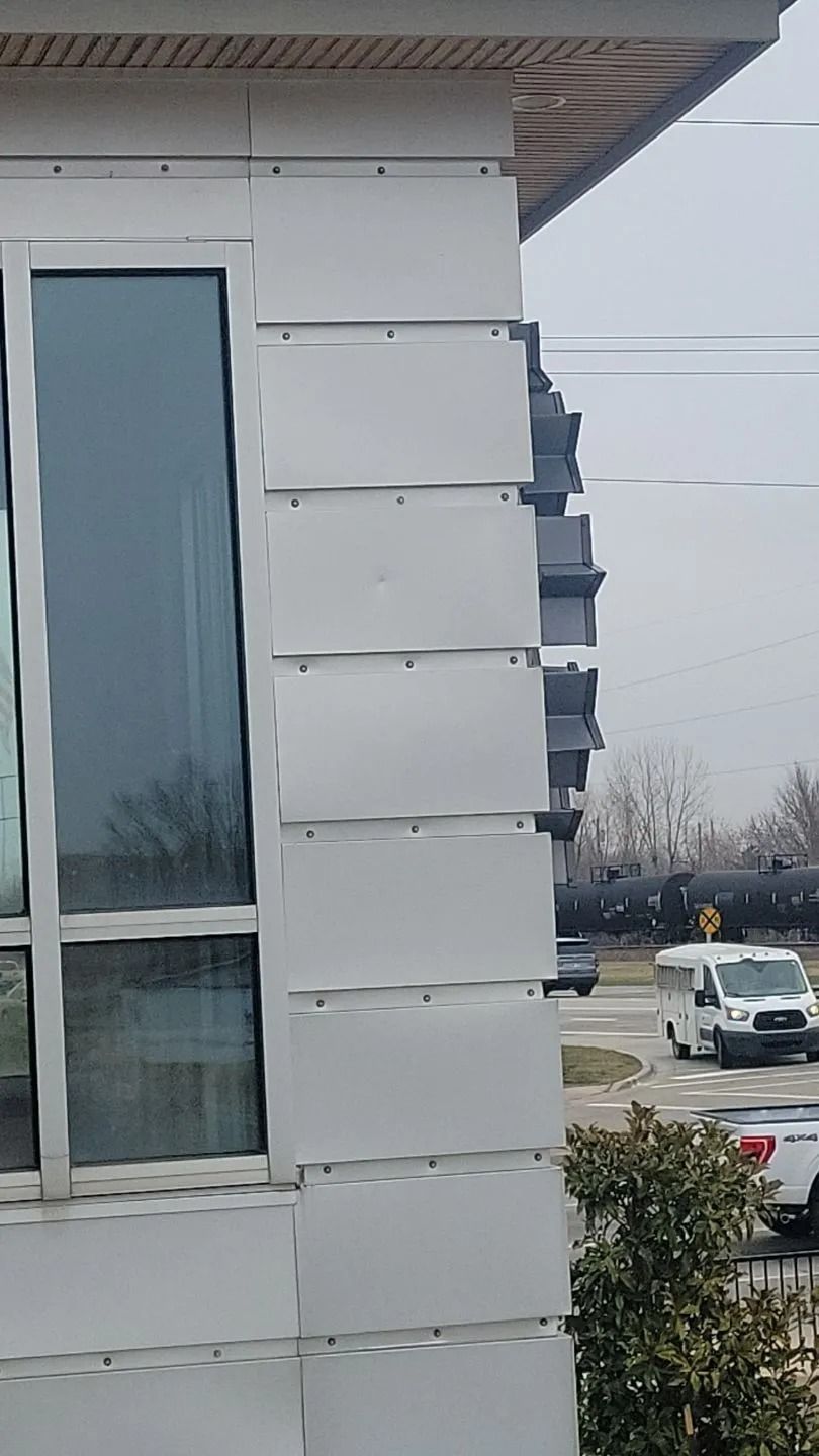 Exterior wall with white, overlapping siding panels near a window.