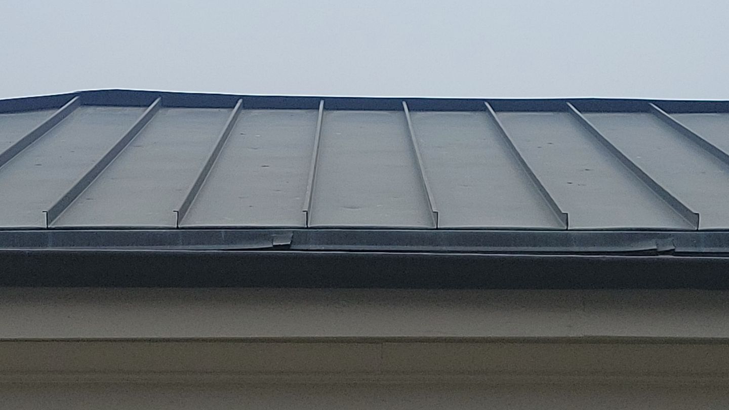 Gray metal roof with raised seams and dark trim.