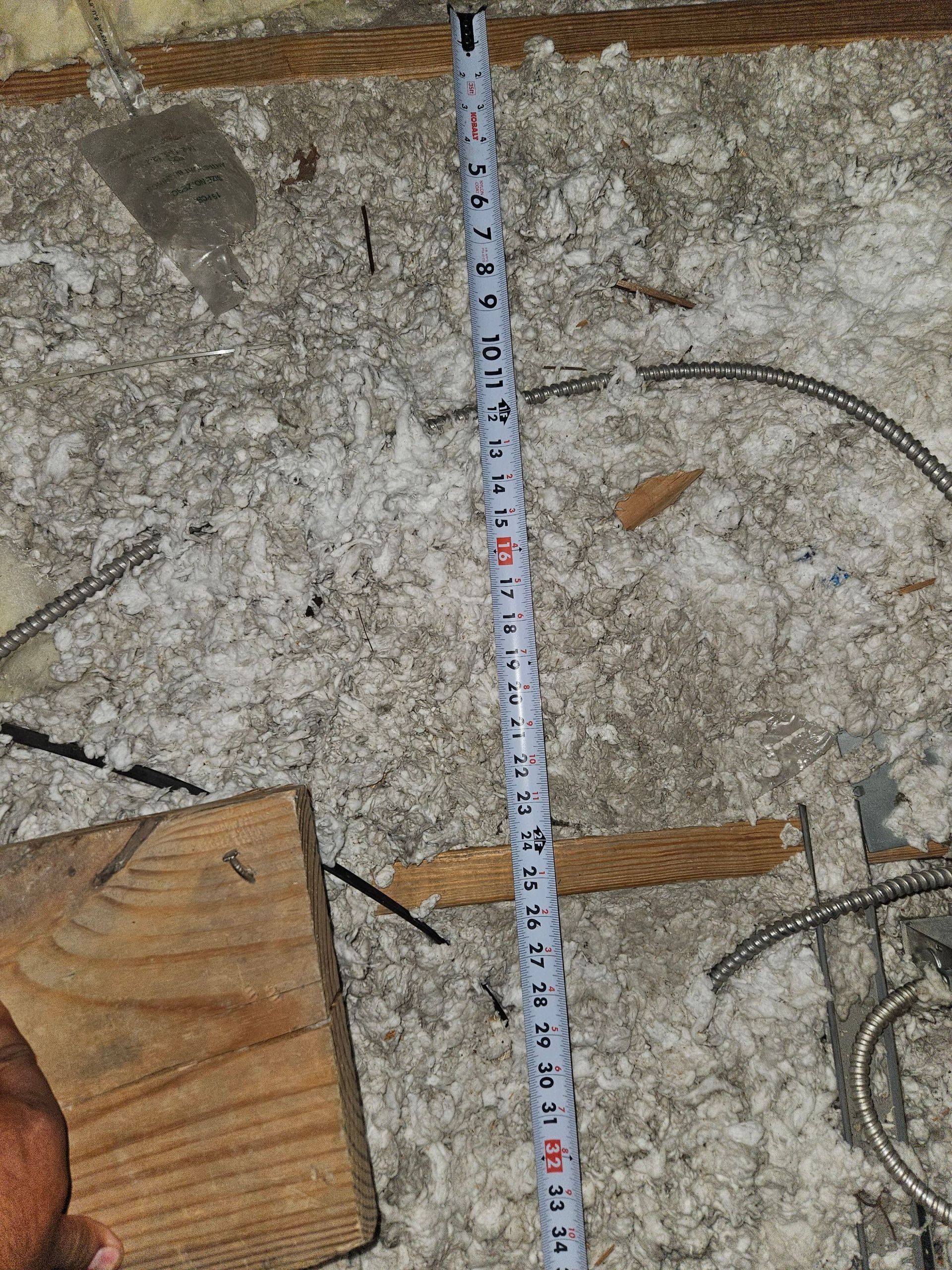 Tape measure on a concrete surface with exposed rebar, a wooden block, and debris.