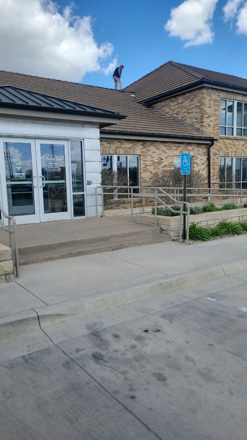 A man stands on a building's roof with a blue handicap parking sign in front.