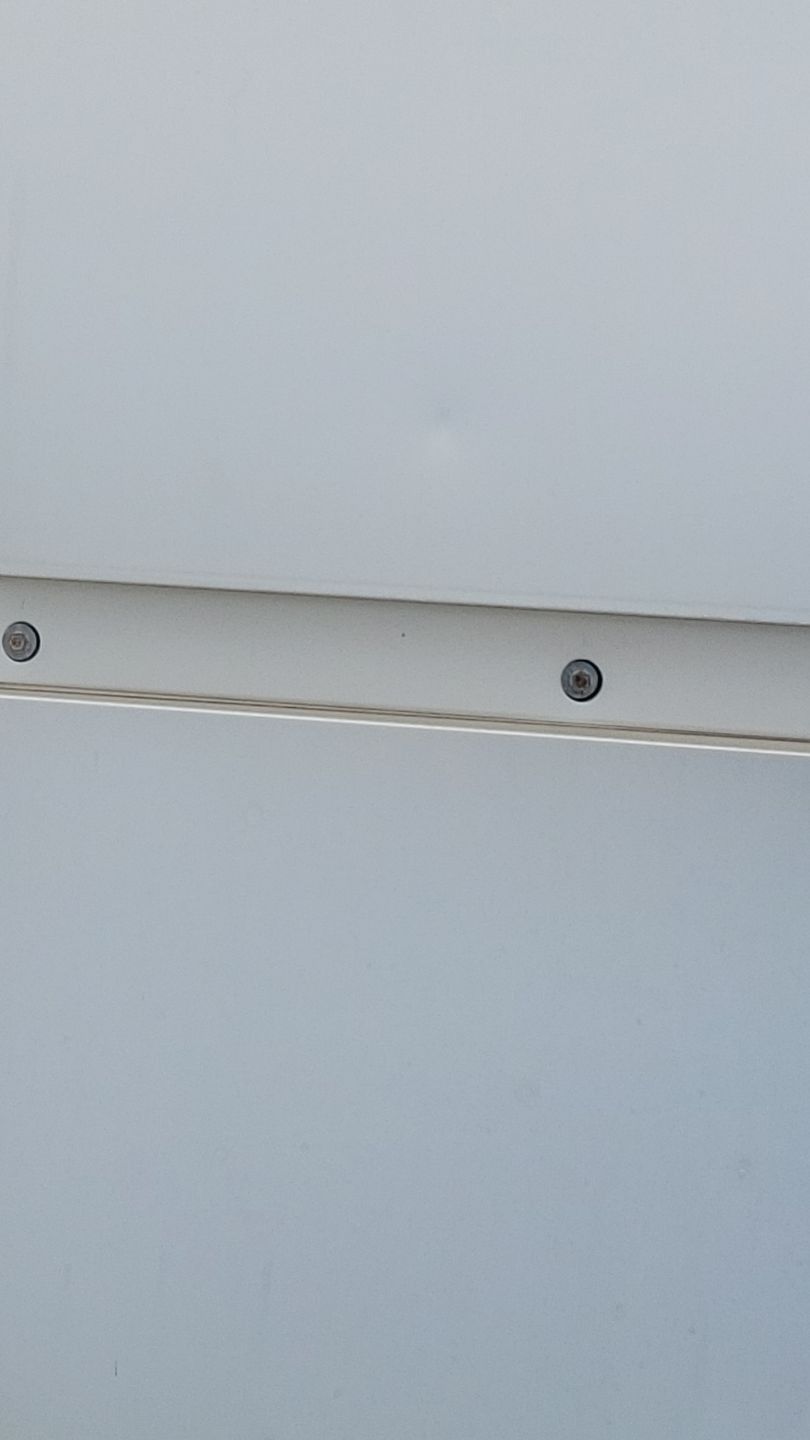 White surface with a thin, light-colored strip secured by two screws.