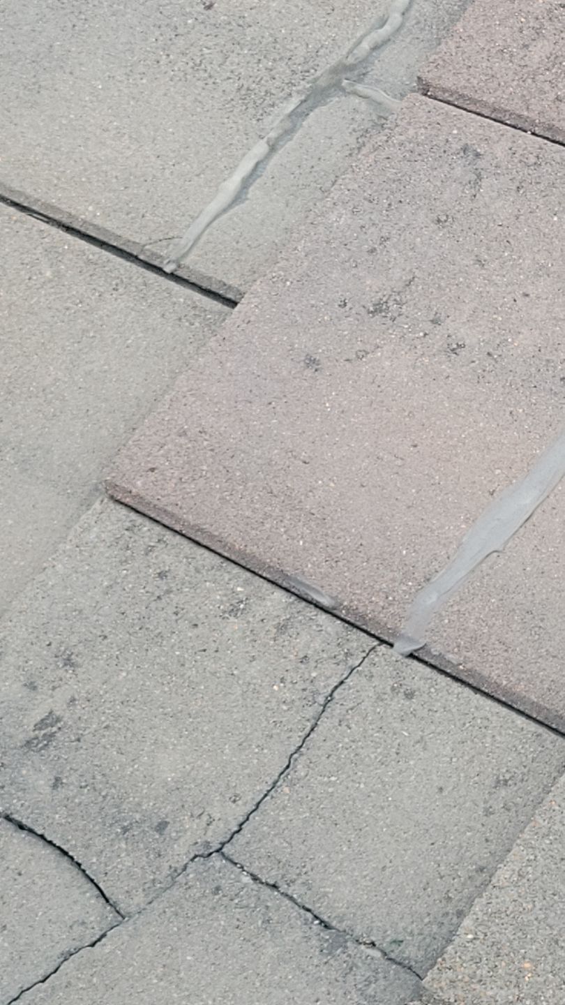Gray concrete paving stones with cracks and sealant between them.
