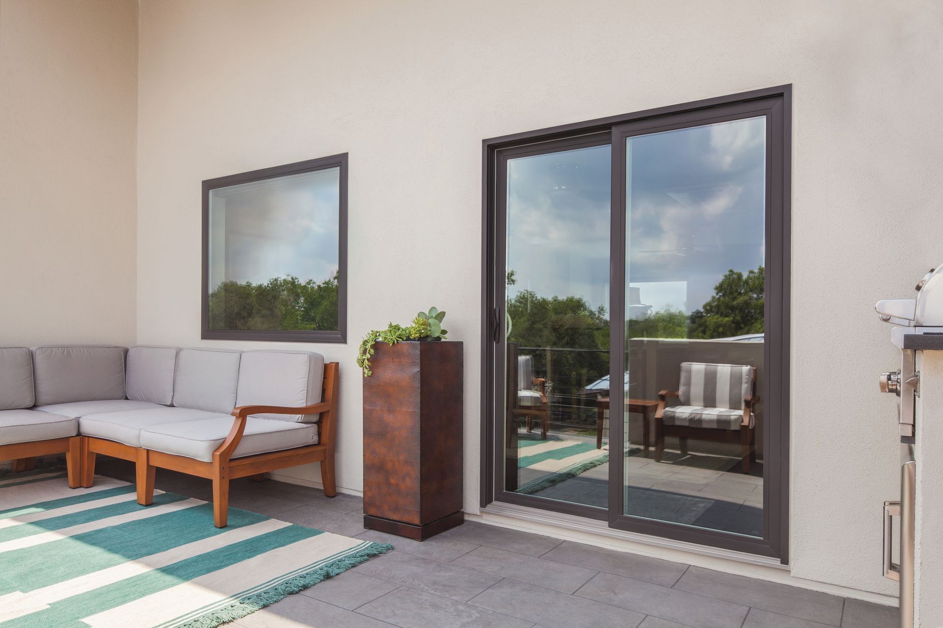 A patio with sliding glass doors and a couch and chairs.