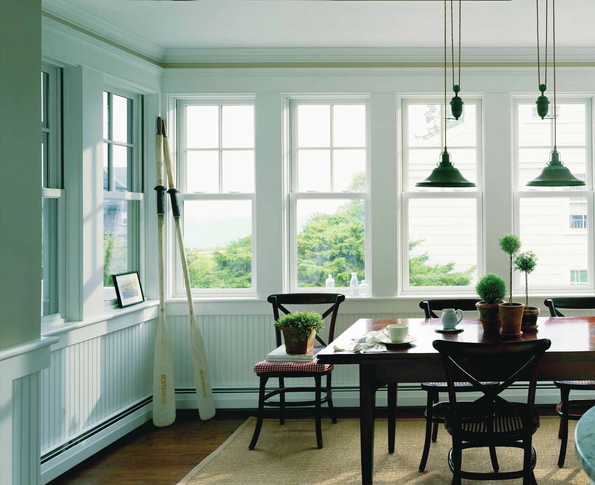 A dining room with a table and chairs and lots of windows