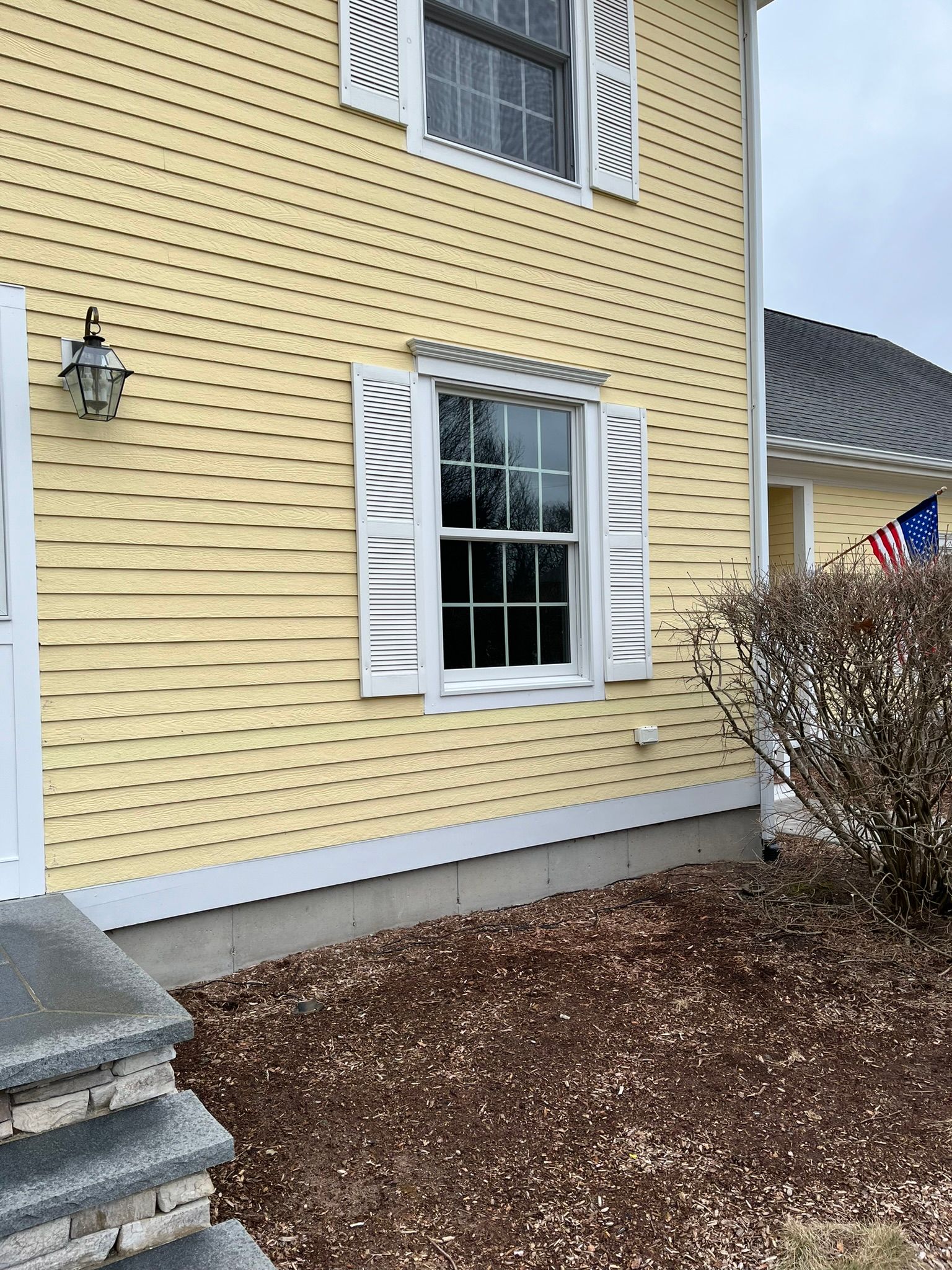 A yellow house with white shutters on the windows