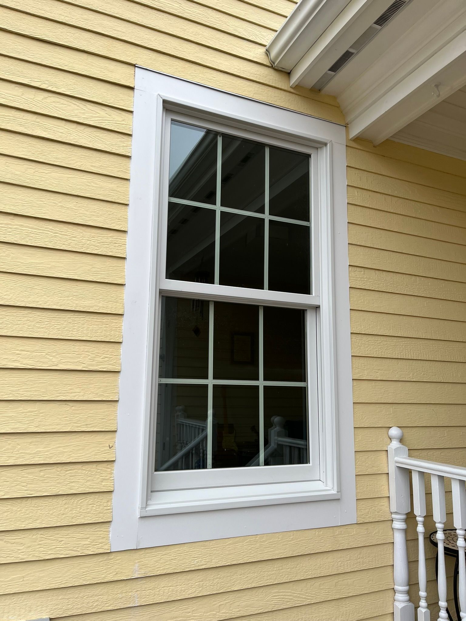 A yellow house with a white window on the side.