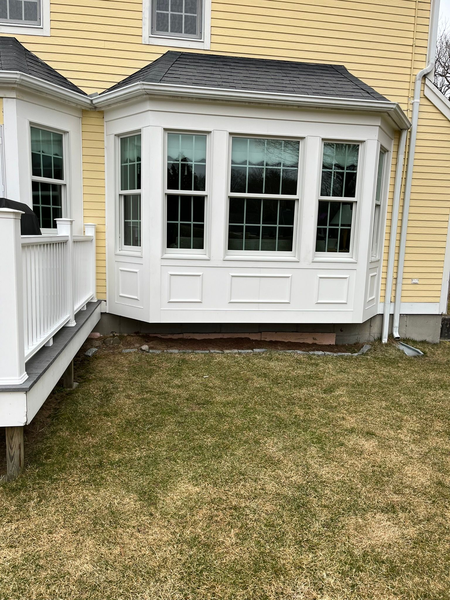 A yellow house with a white porch and a bay window.