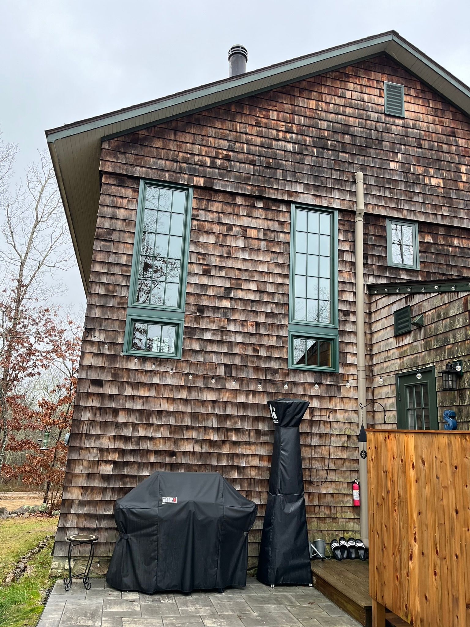 A large wooden house with a grill on the side of it.