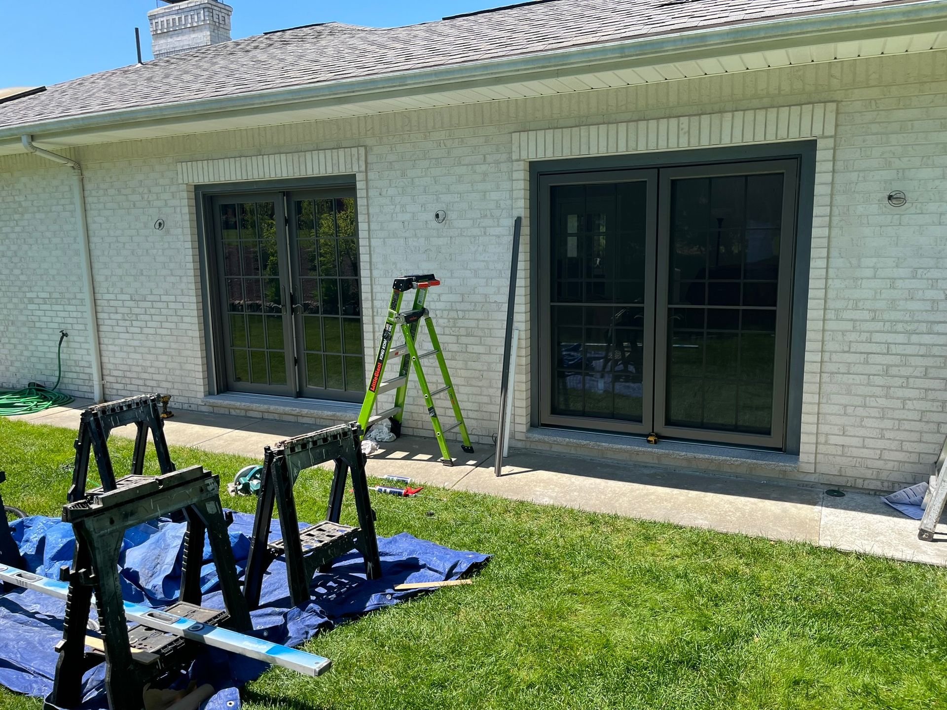 A white brick house with sliding glass doors is being painted.