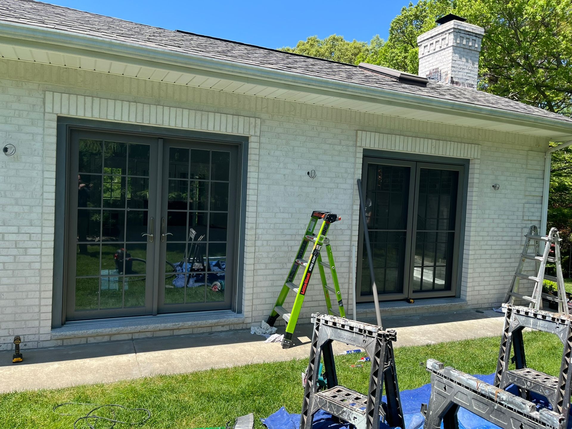 A white brick house with sliding glass doors is being painted.