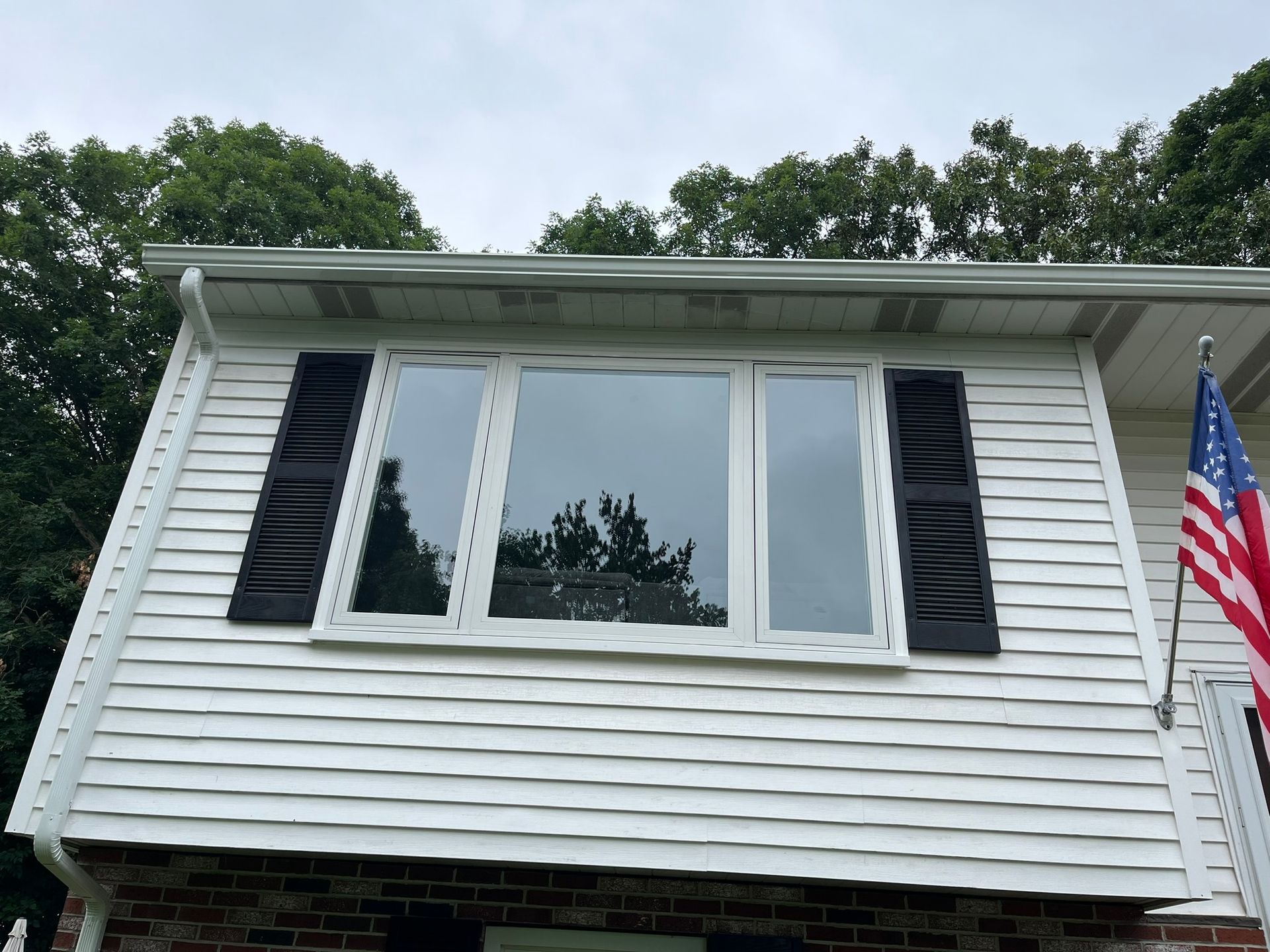 A white house with black shutters and an american flag