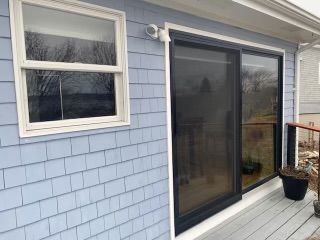 A blue house with a sliding glass door and two windows.