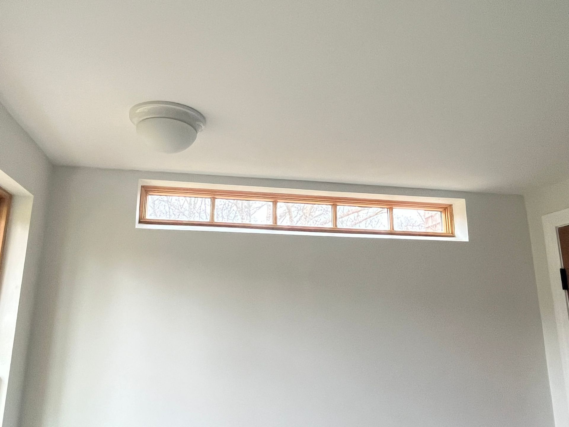 A room with a window and a light on the ceiling.