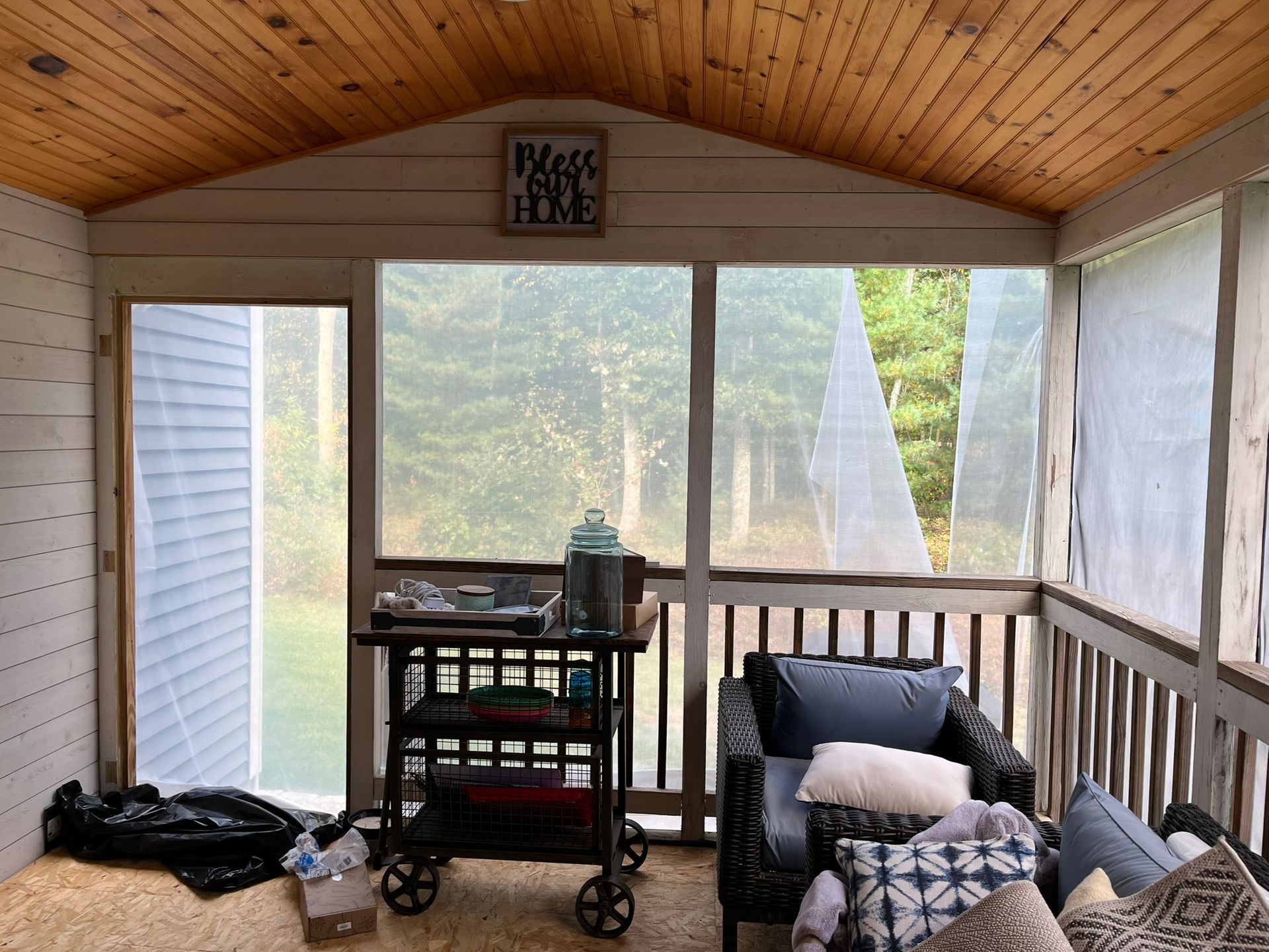 A screened in porch with a chair and a cart.