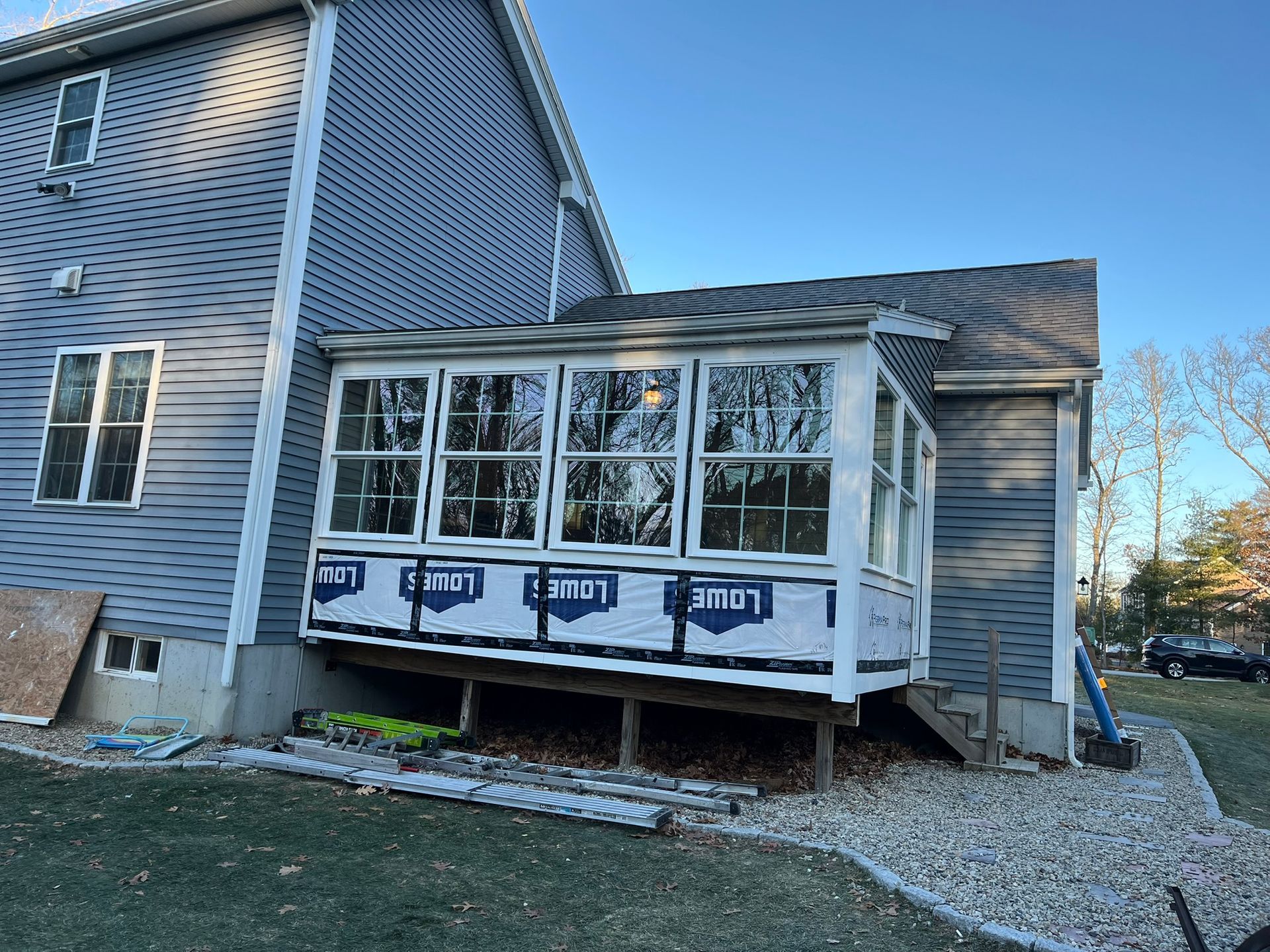 A house with a sunroom being built on the side of it.