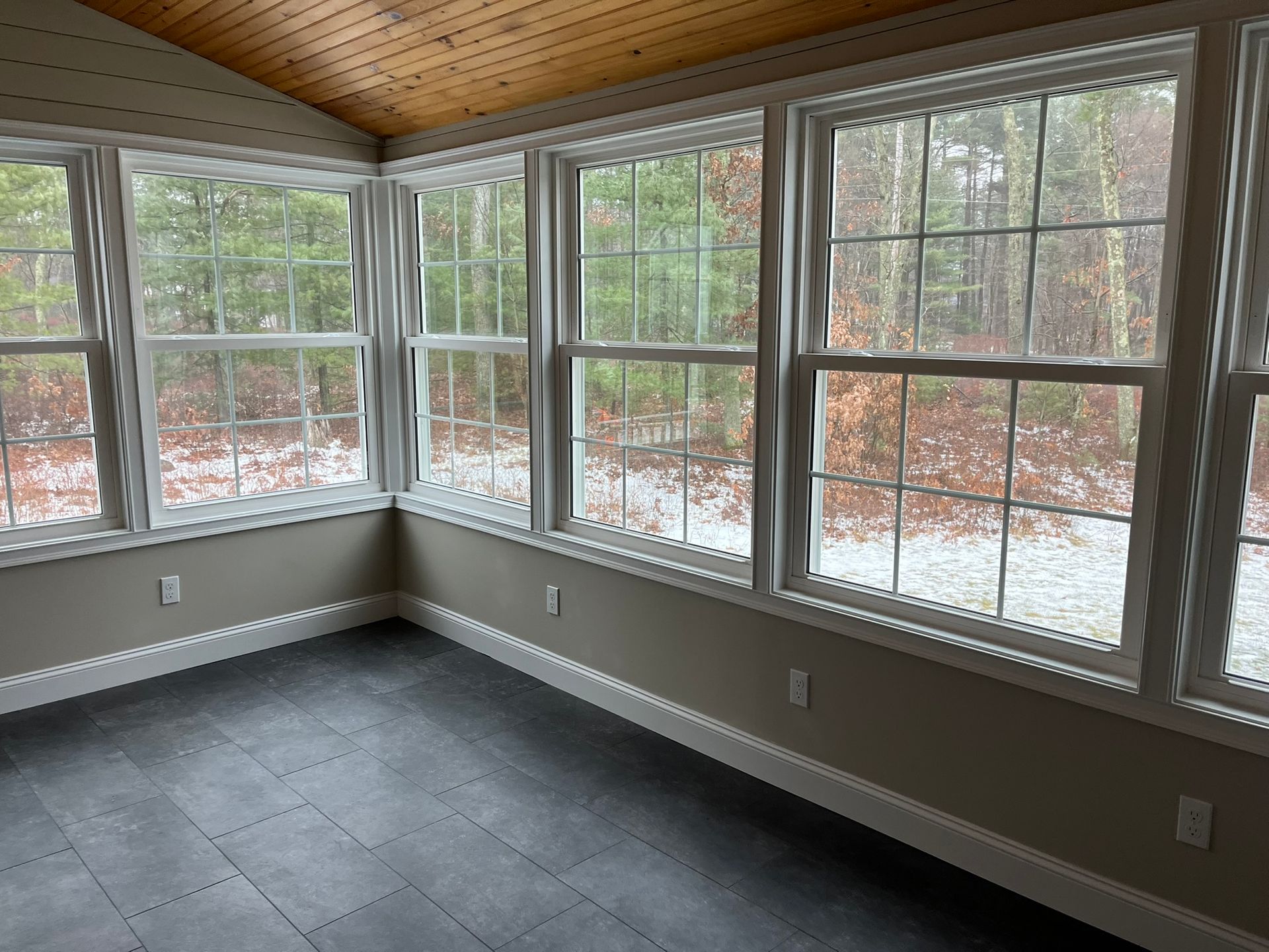 An empty room with a lot of windows and a wooden ceiling.