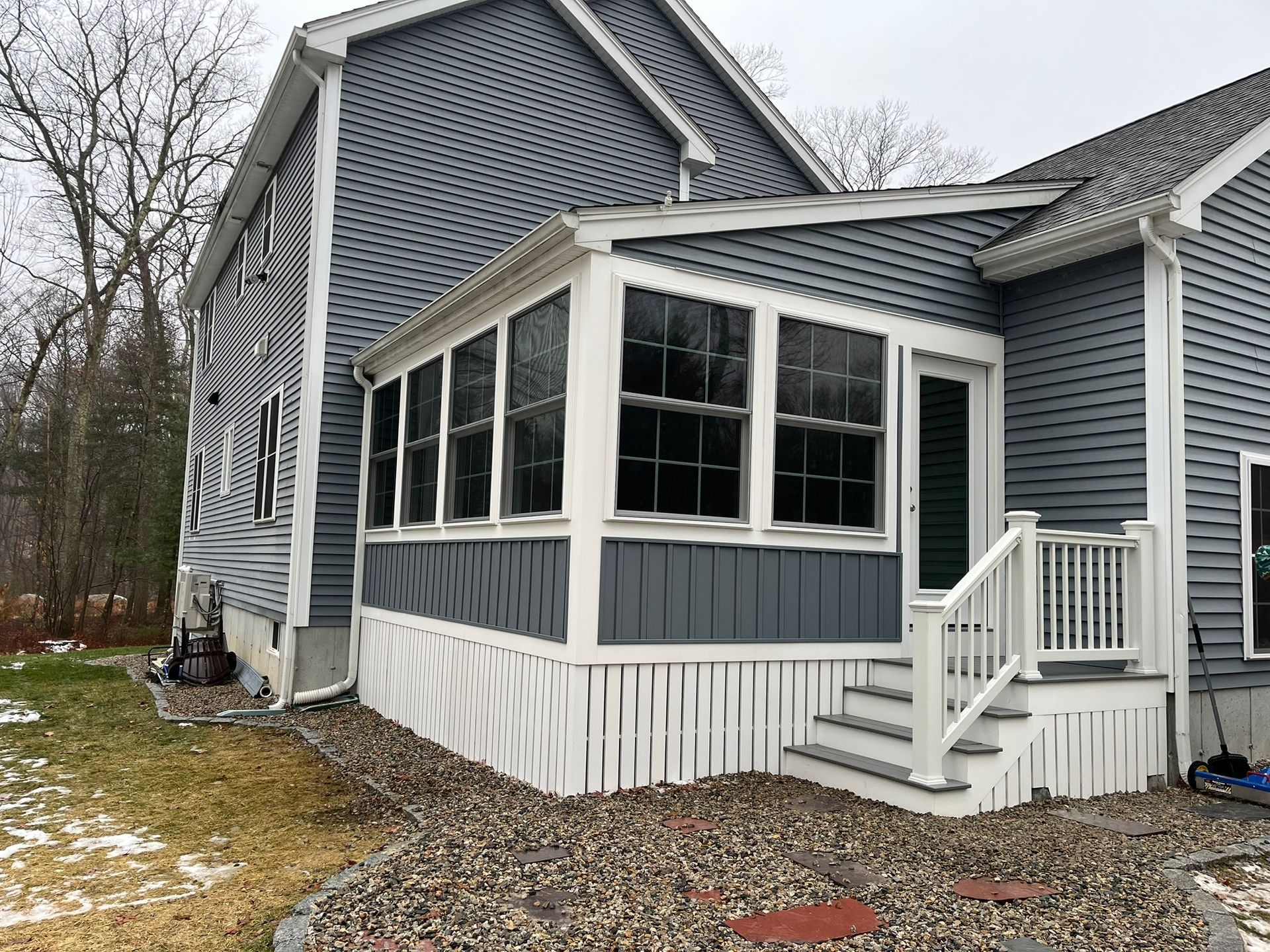 The back of a house with a screened in porch and stairs.