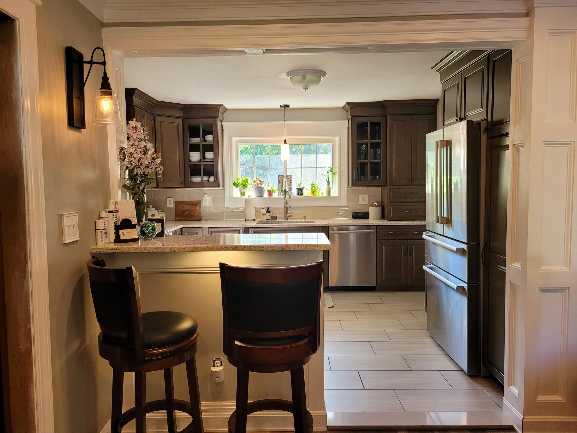 A kitchen with stainless steel appliances and a bar with two chairs.