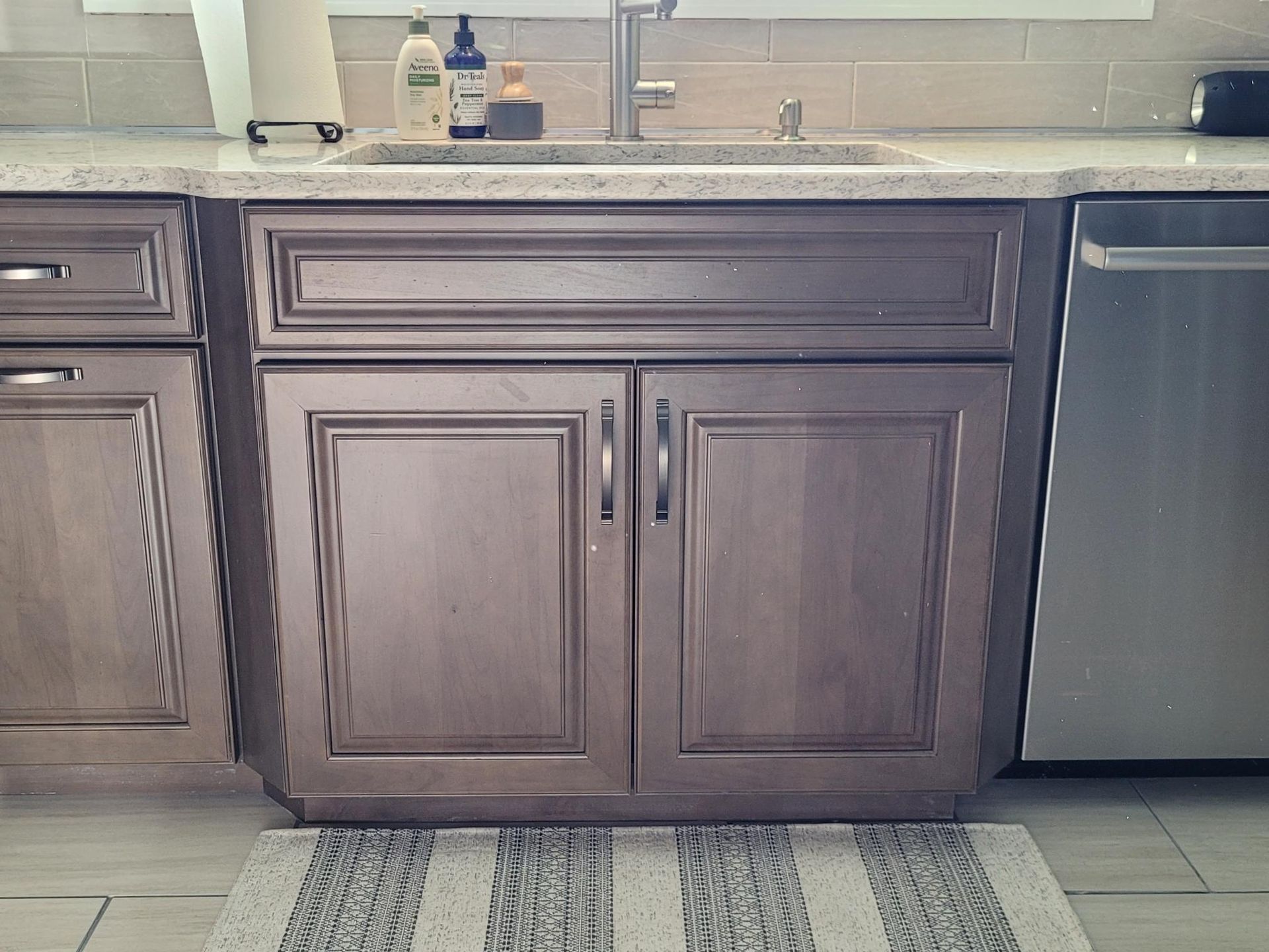 A kitchen with a sink , cabinets , and a stainless steel dishwasher.