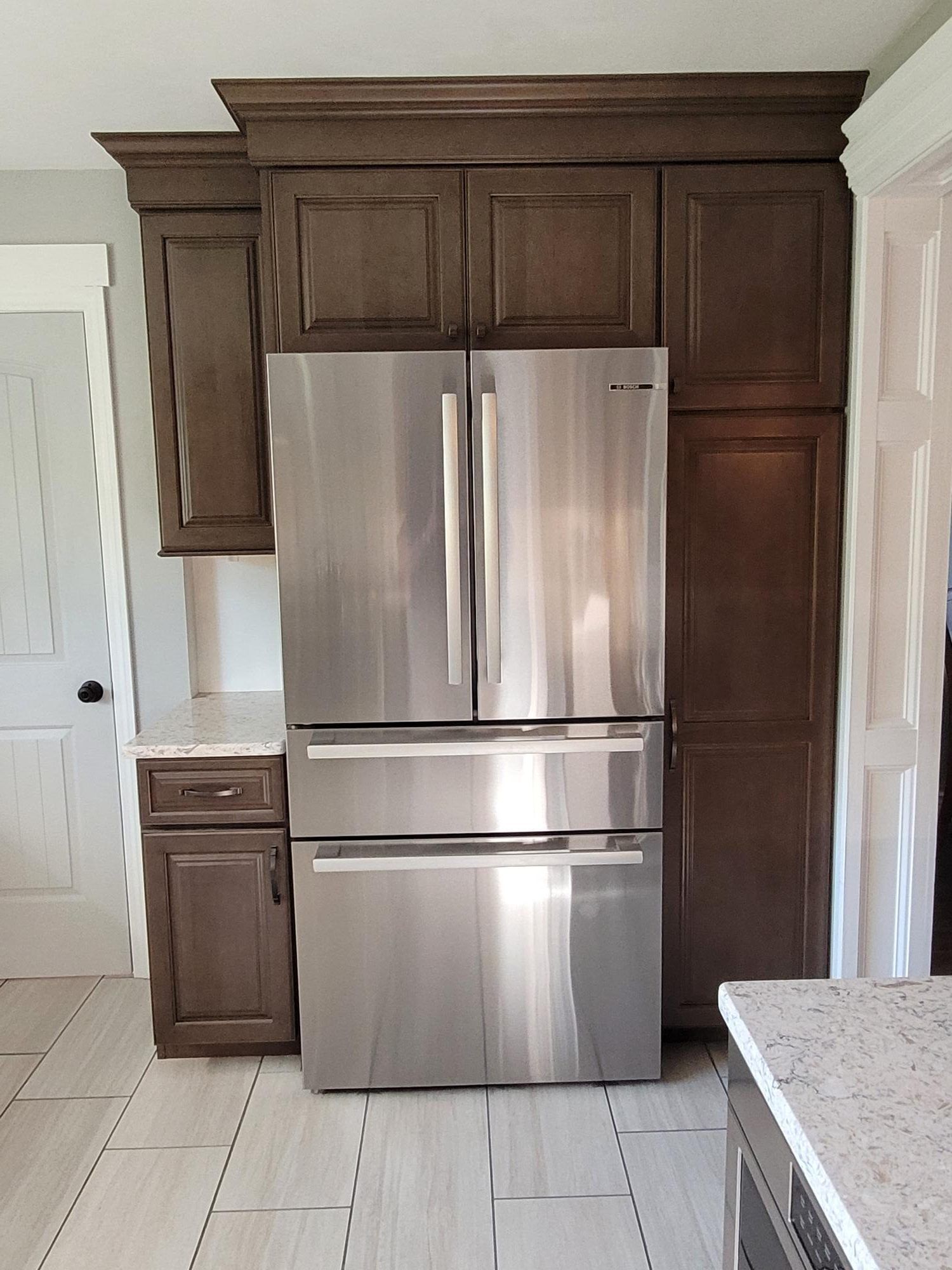A stainless steel refrigerator in a kitchen with wooden cabinets