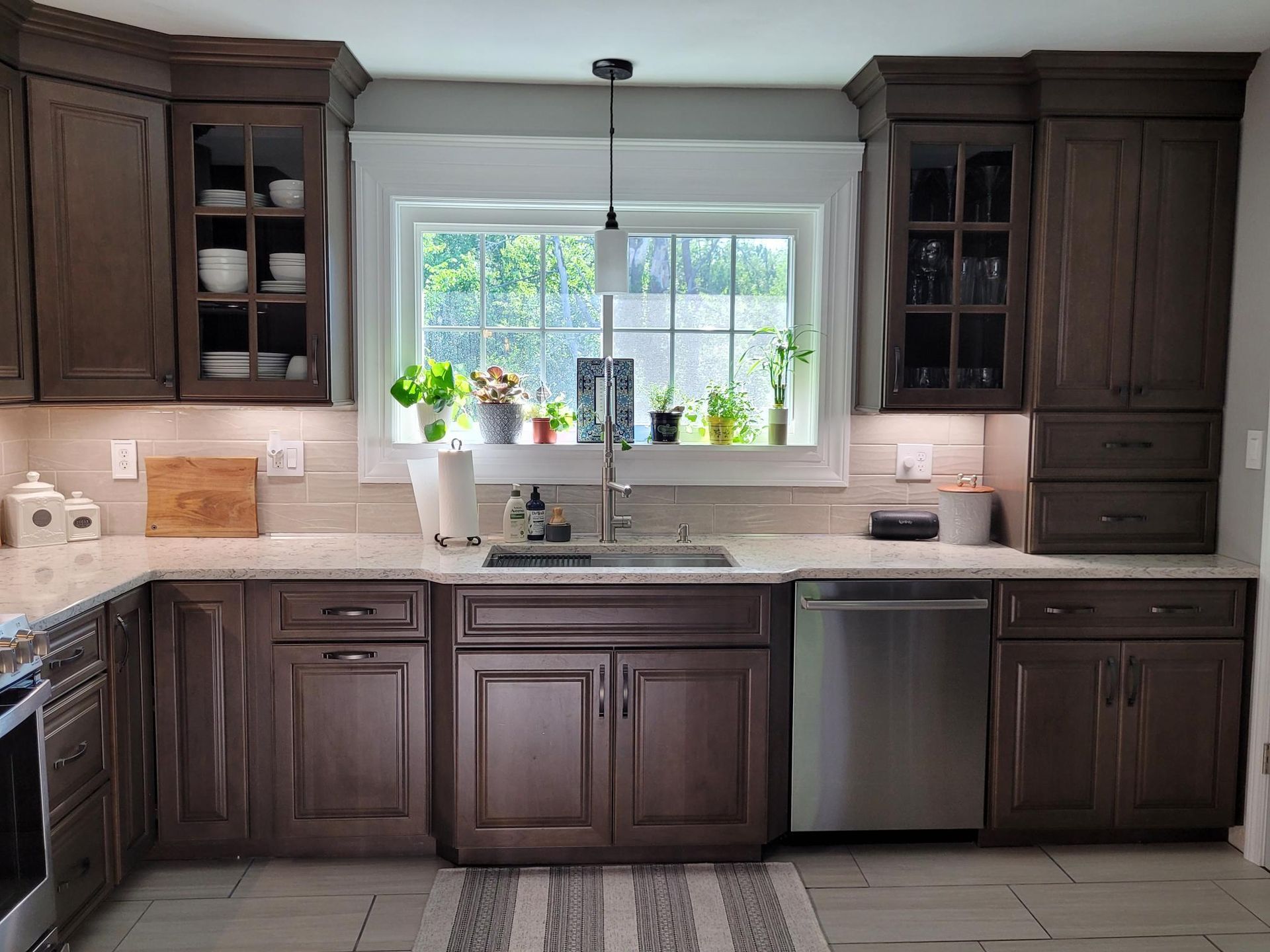 A kitchen with wooden cabinets , stainless steel appliances , a sink , and a window.