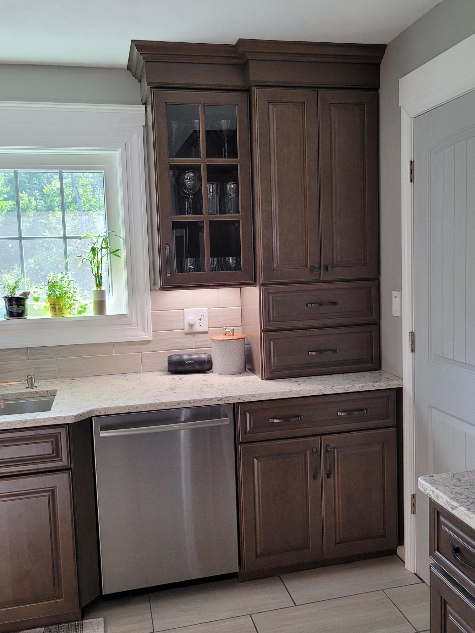 A kitchen with wooden cabinets , stainless steel appliances , a sink , and a window.