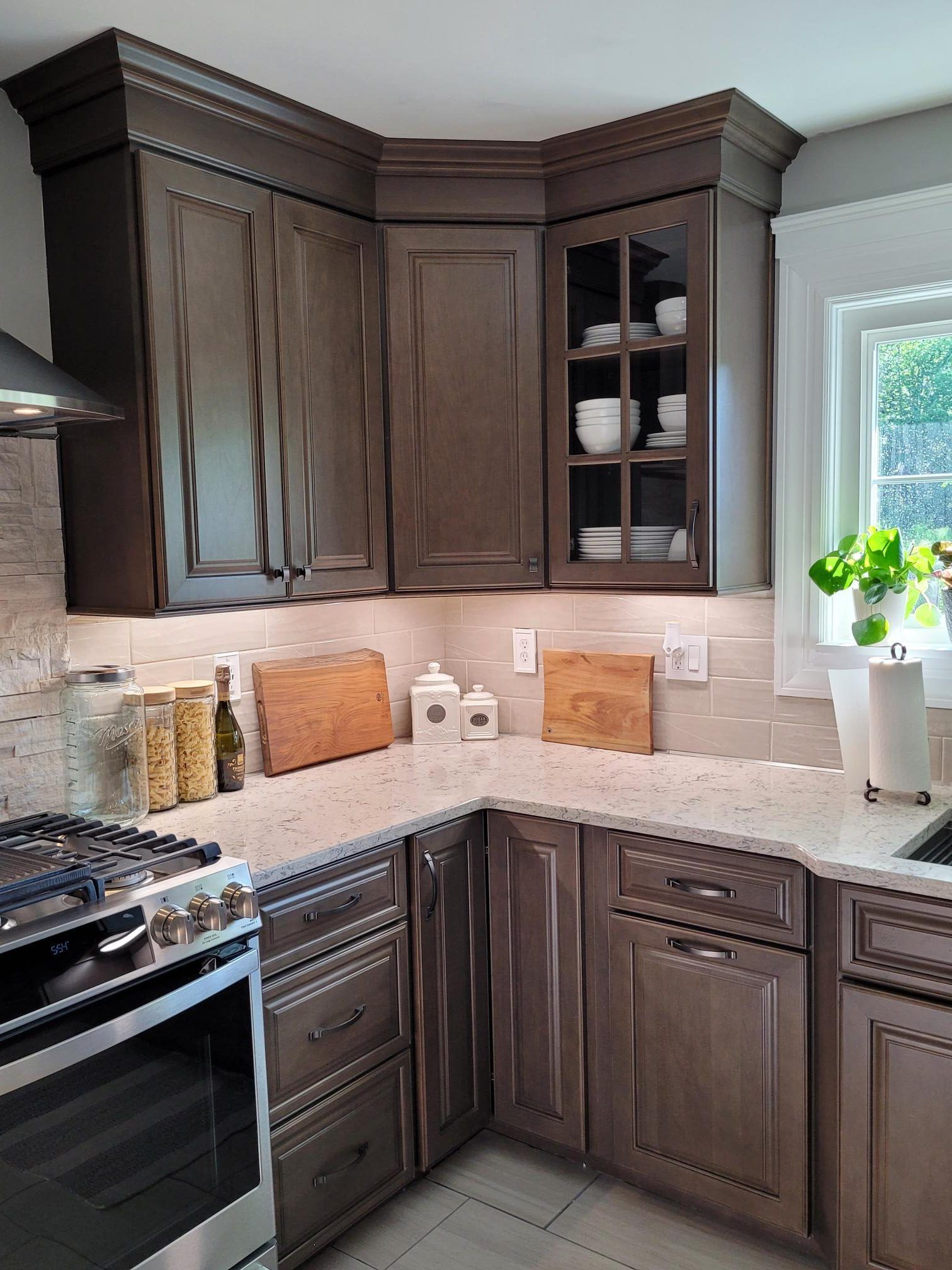 A kitchen with a stove , sink , cabinets and a window.
