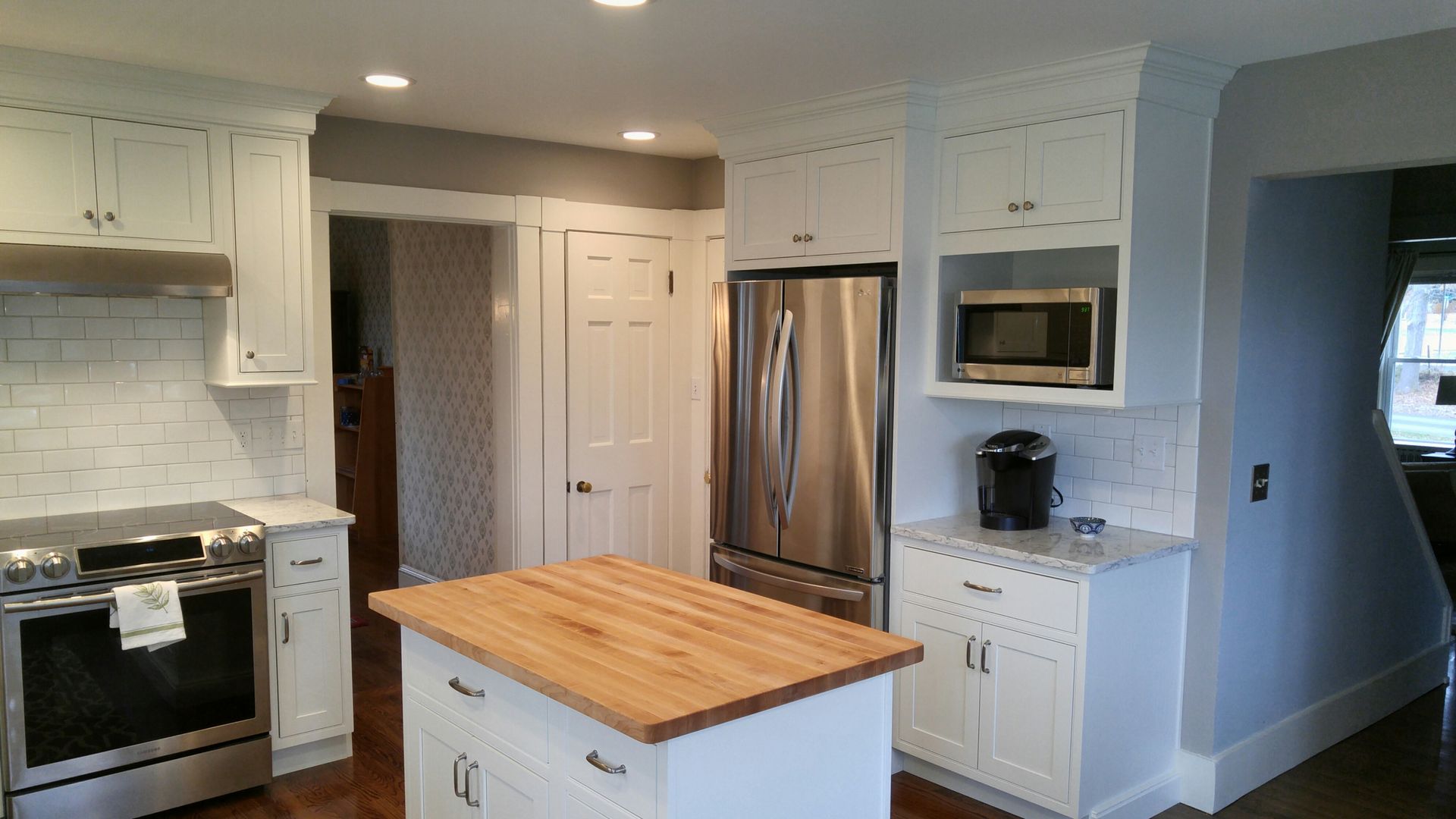 A kitchen with white cabinets , stainless steel appliances and a wooden island.