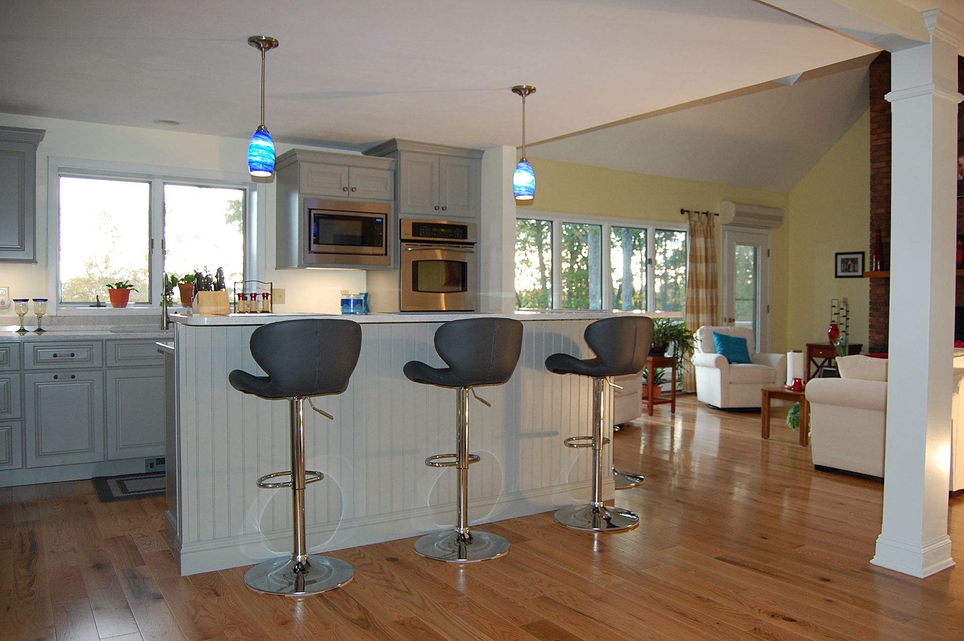 A kitchen with three bar stools and a microwave