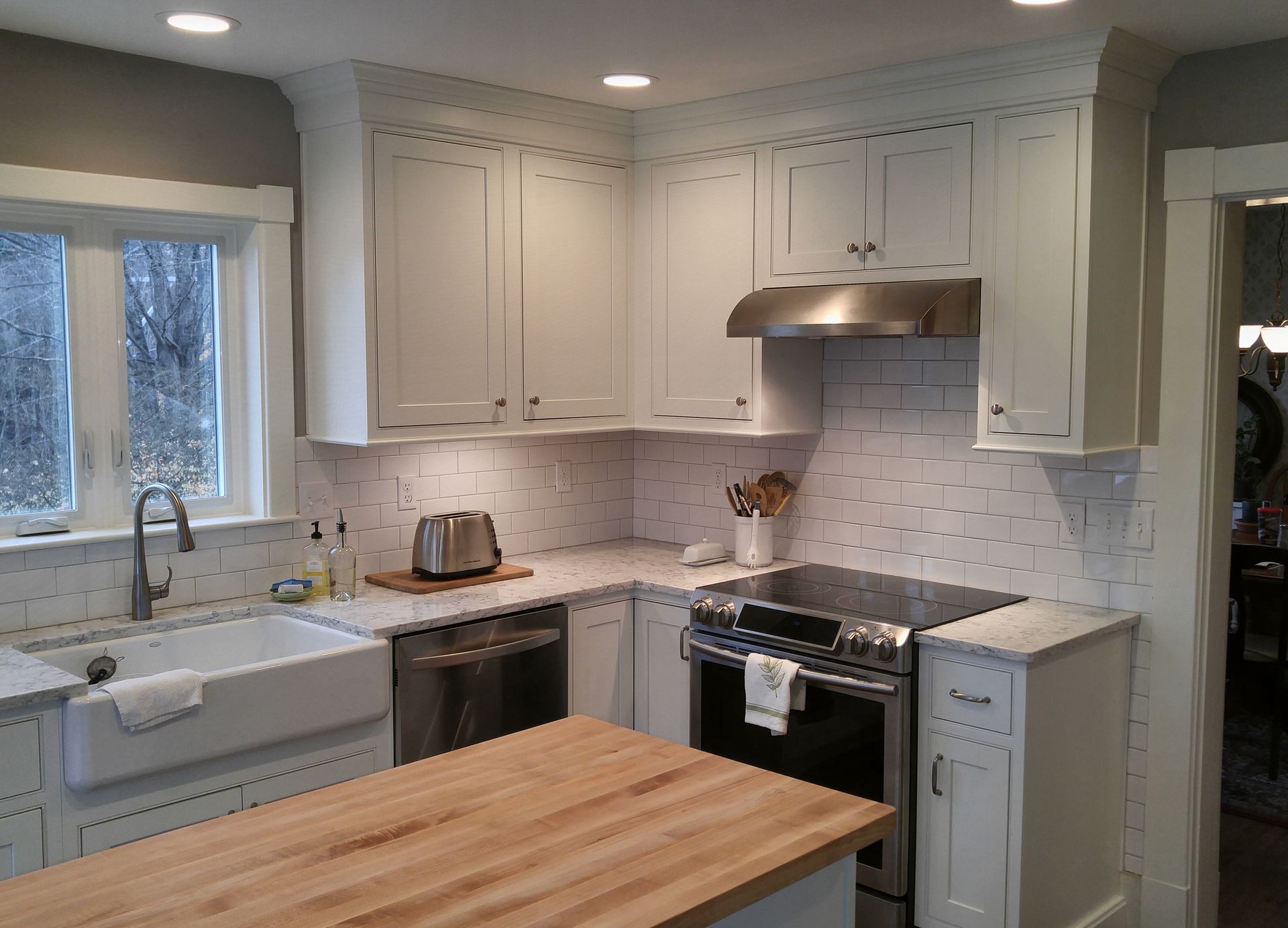 A kitchen with white cabinets and a wooden counter top