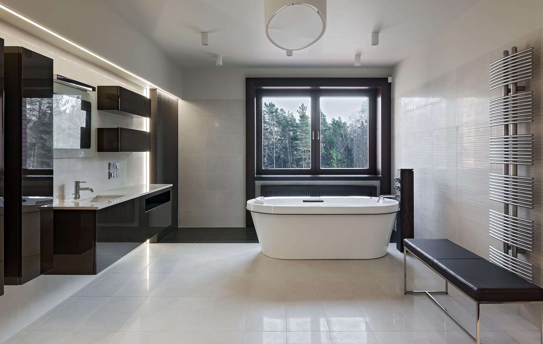 A bathroom with a tub , sink , mirror and window.