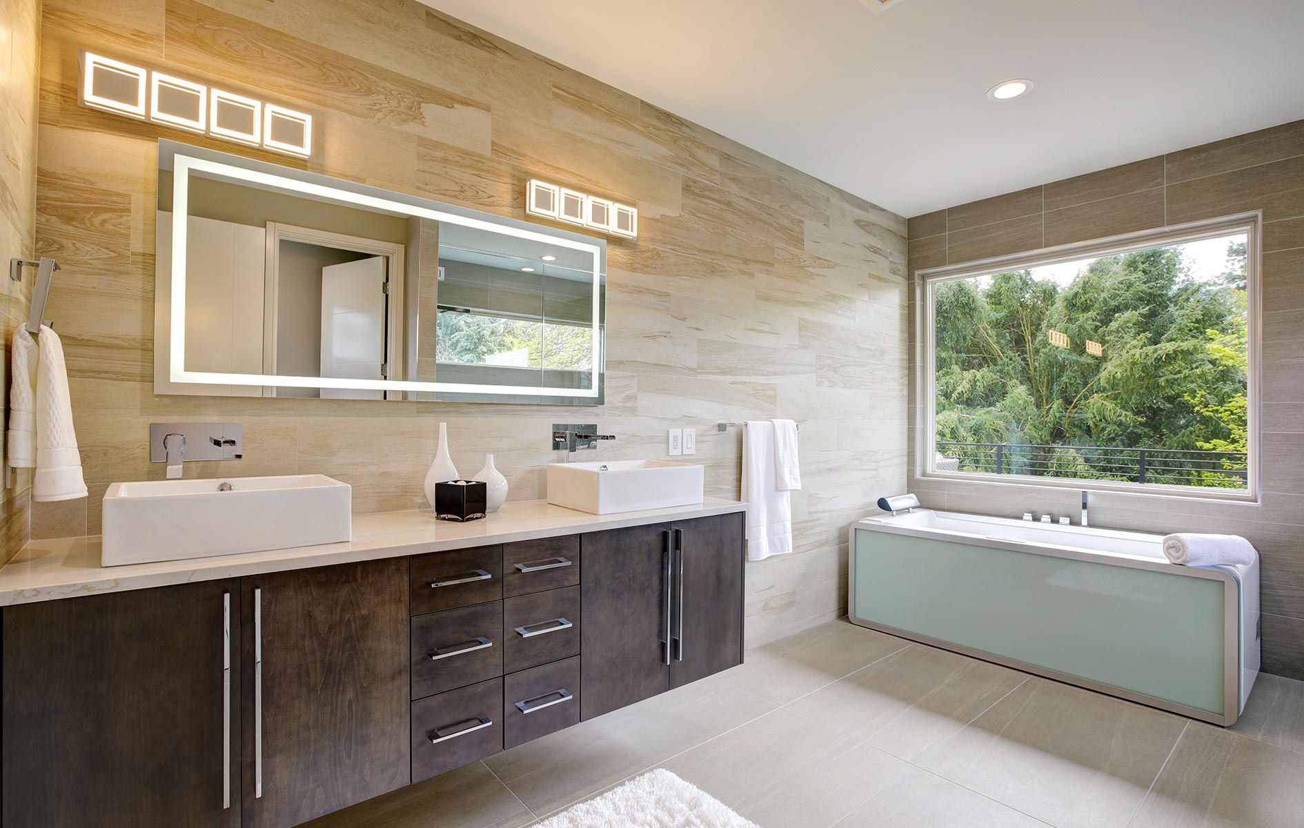 A bathroom with two sinks , a tub and a large mirror.