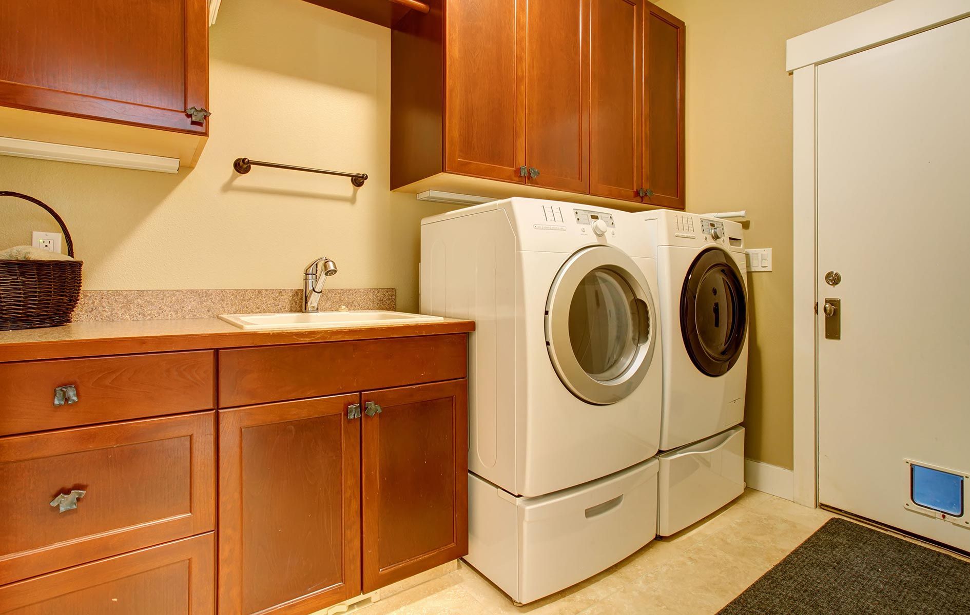 A laundry room with a washer and dryer and wooden cabinets.