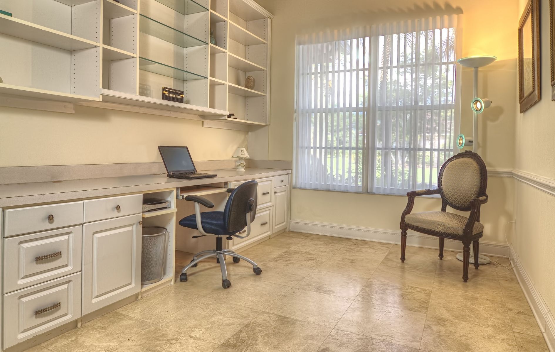 A home office with a desk , chair , and shelves.