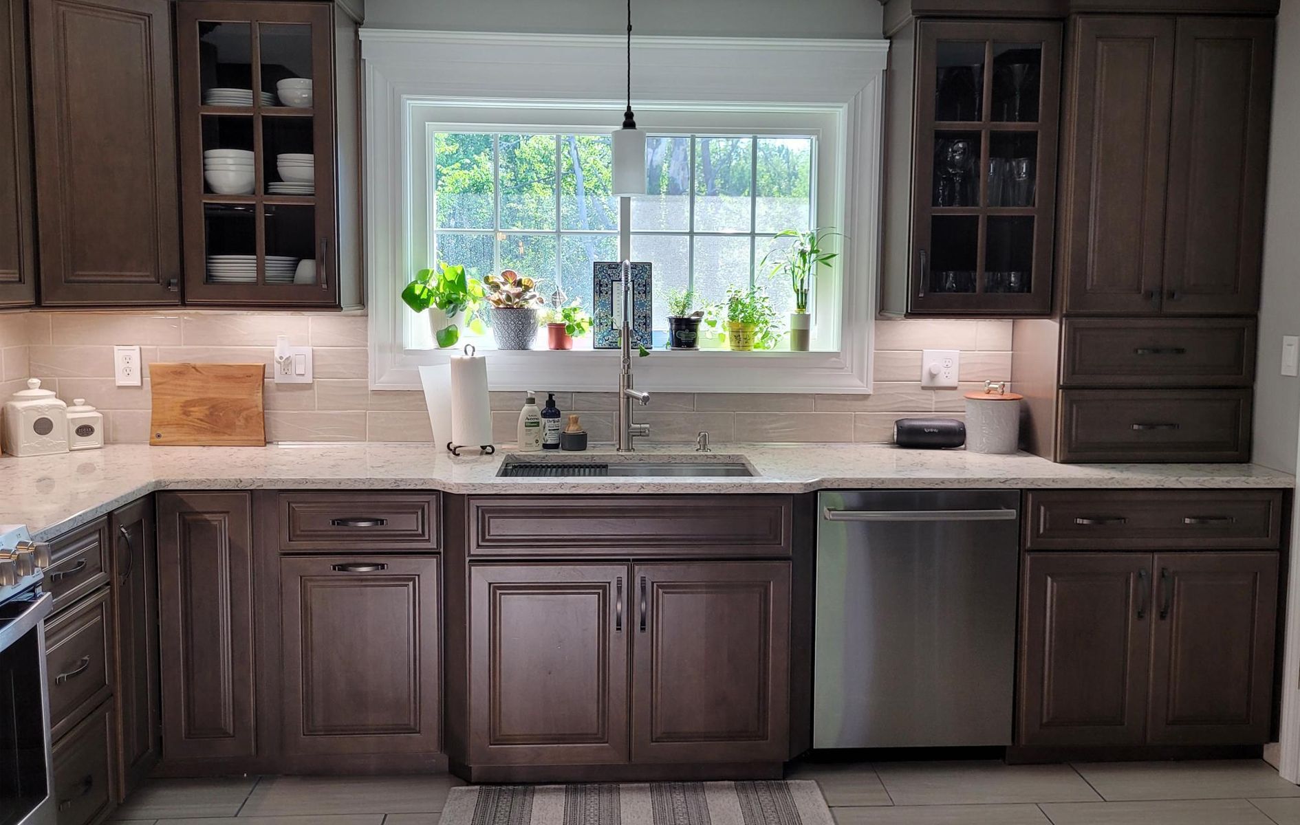A kitchen with brown cabinets , stainless steel appliances , a sink , and a window.