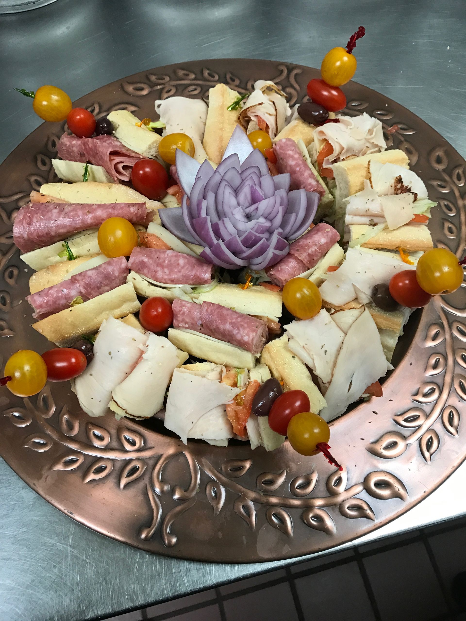 Decorative appetizer platter with assorted cheeses, meats, and cherry tomatoes