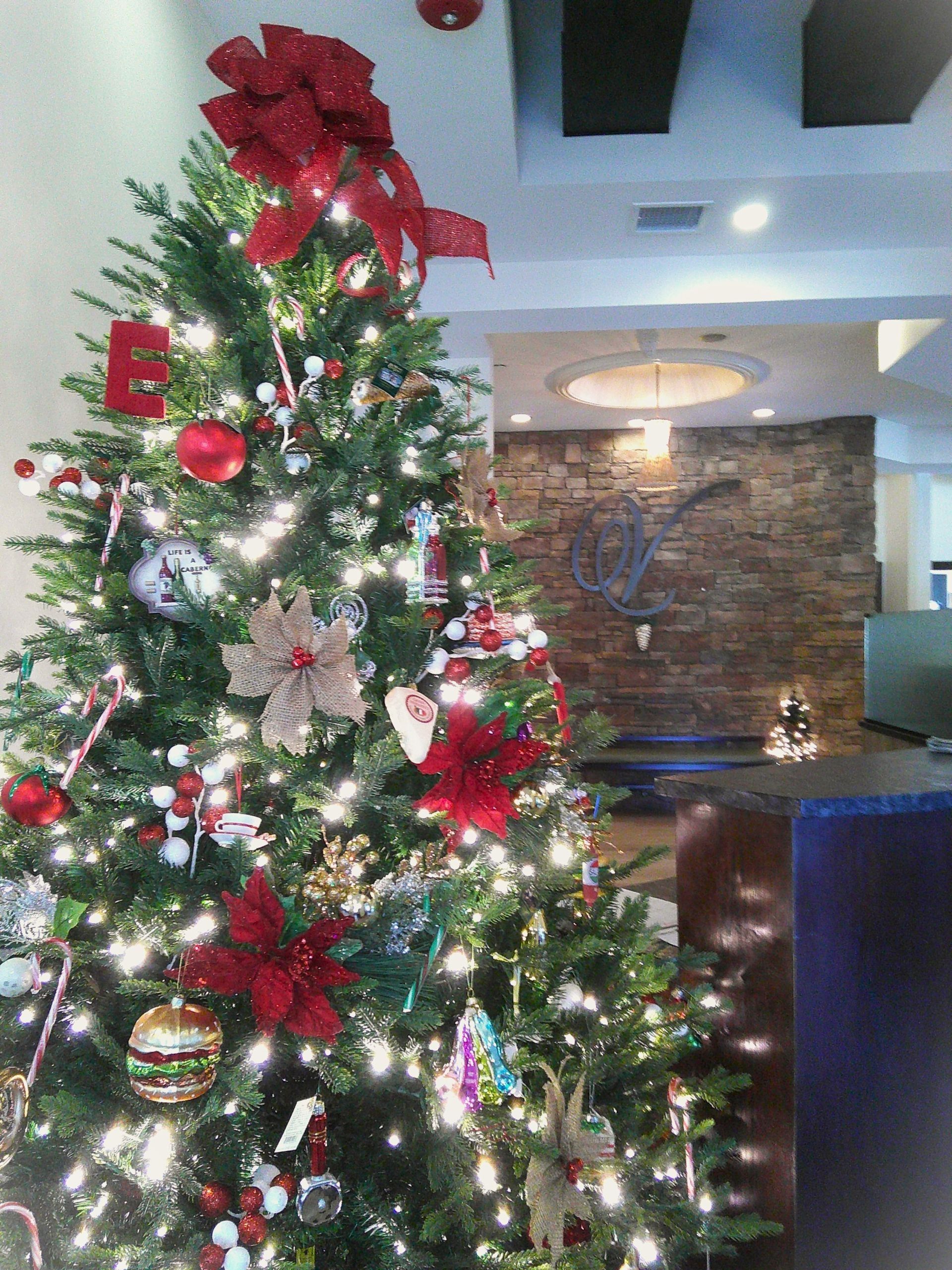 Christmas tree decorated with ornaments and lights in a room with a brick wall.