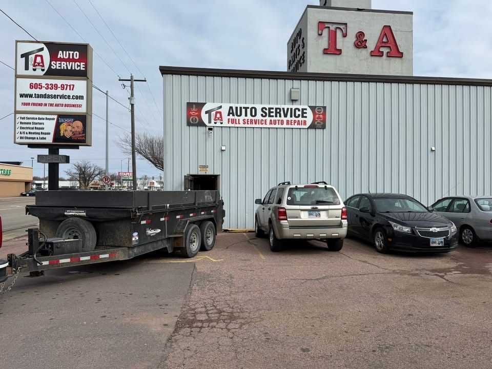 T&A Auto Service storefront with parked cars and a flatbed trailer in front