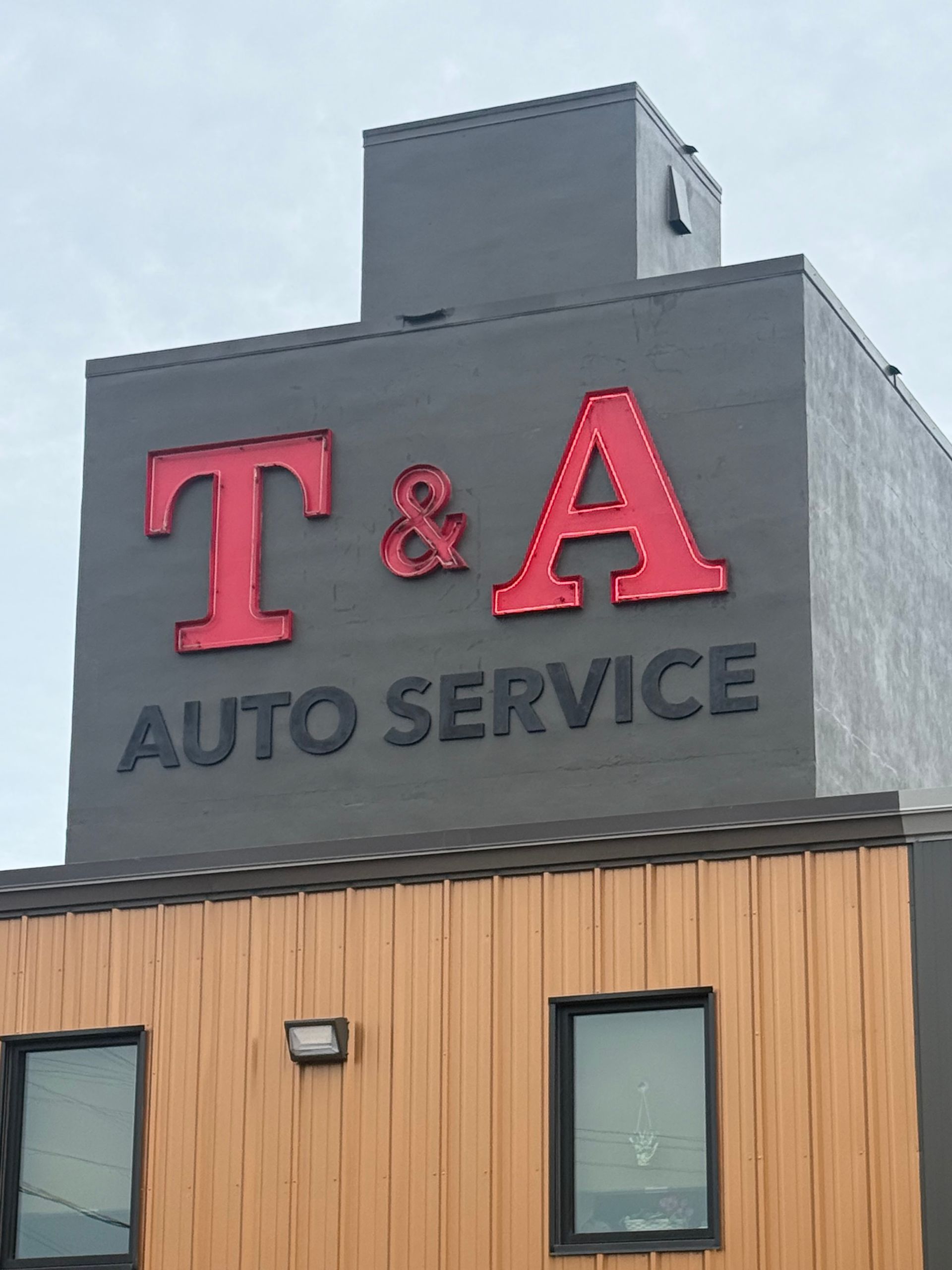 T&A Auto Service storefront with parked cars and a flatbed trailer in front