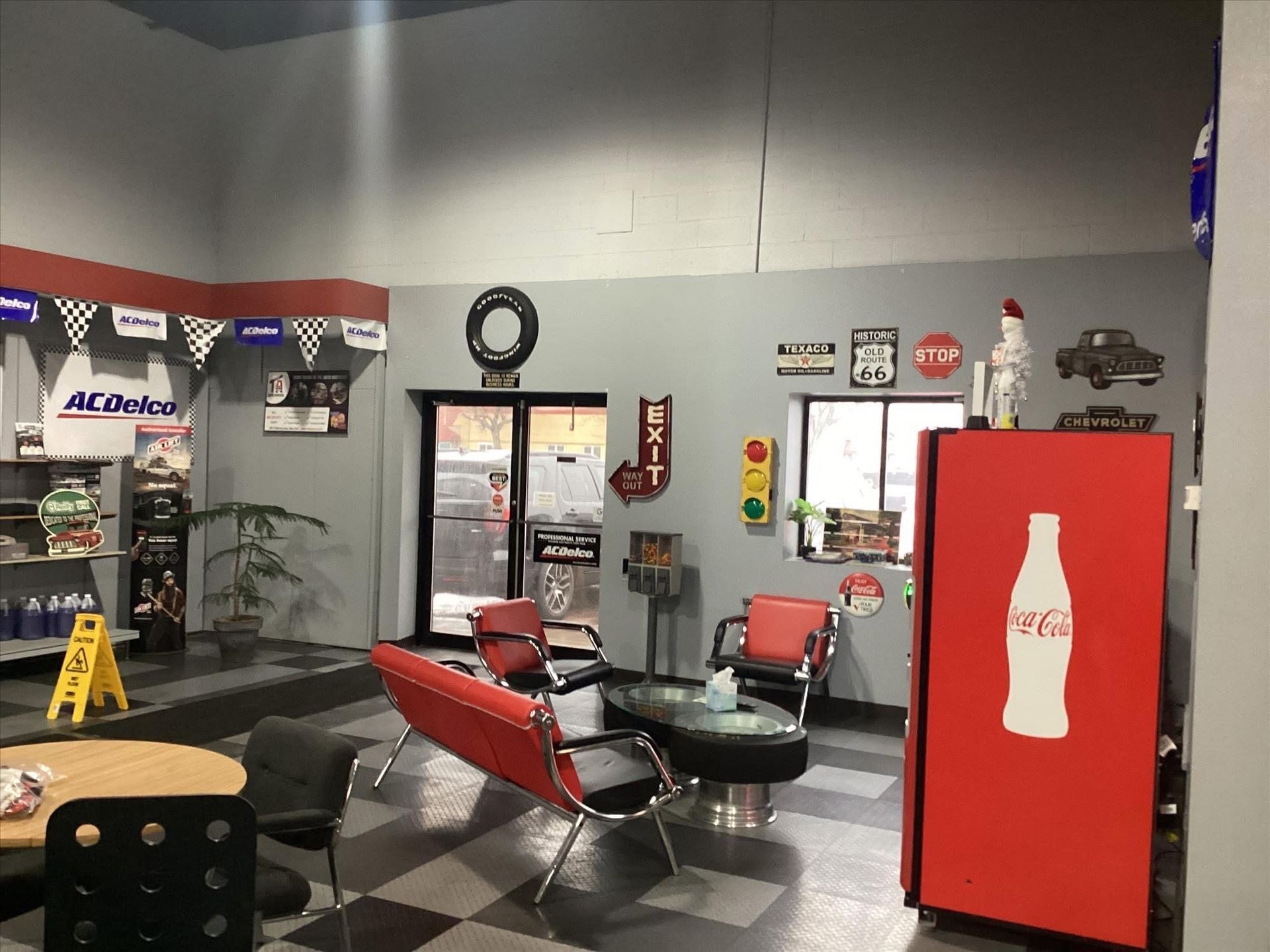 Indoor lounge with red and black chairs, a Coca-Cola fridge, and a wall clock.