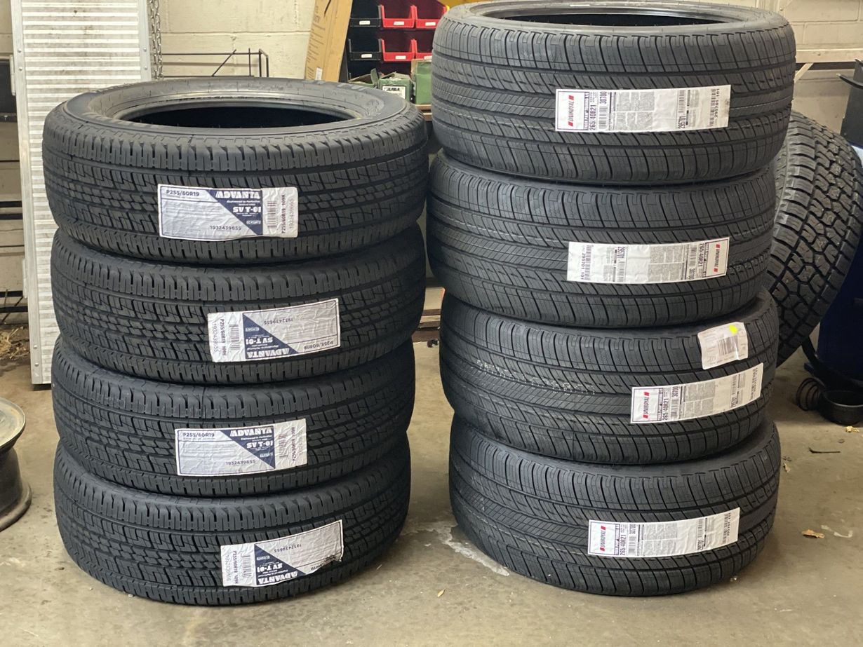 Stacks of black tires with labels, arranged in two columns in a warehouse or shop.
