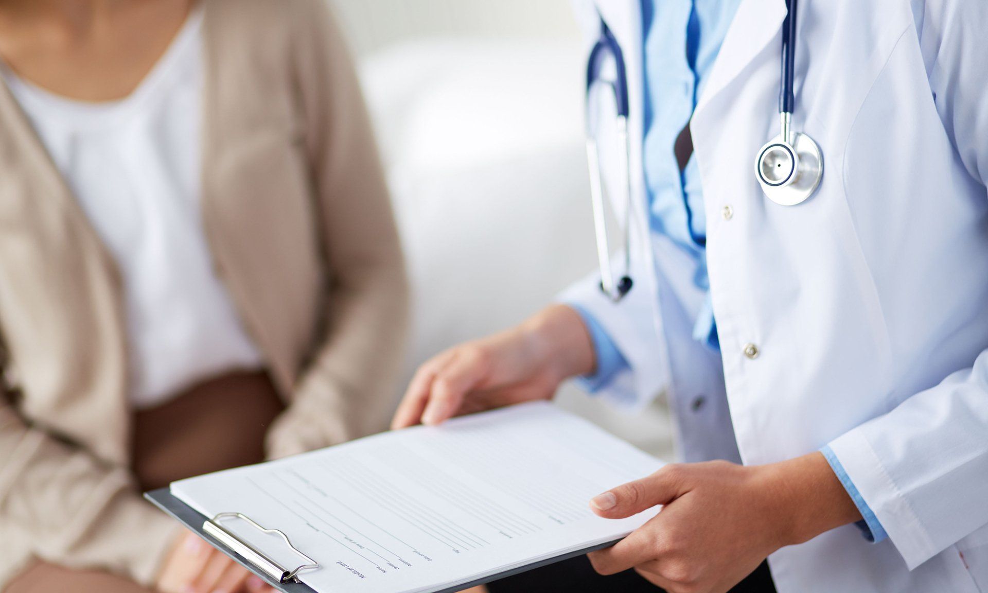 A doctor is holding a clipboard in front of a patient.