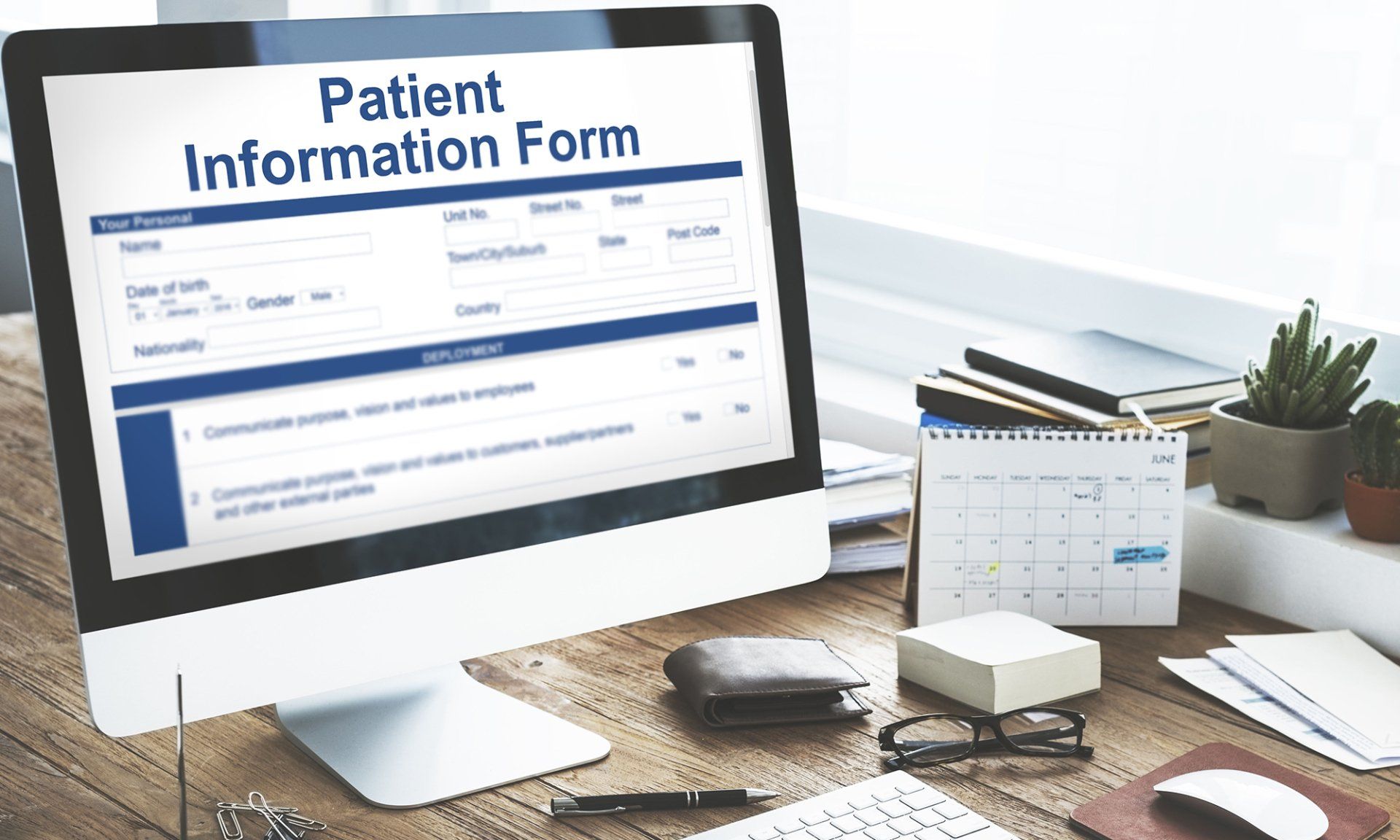A computer monitor displaying a patient information form on a wooden desk.