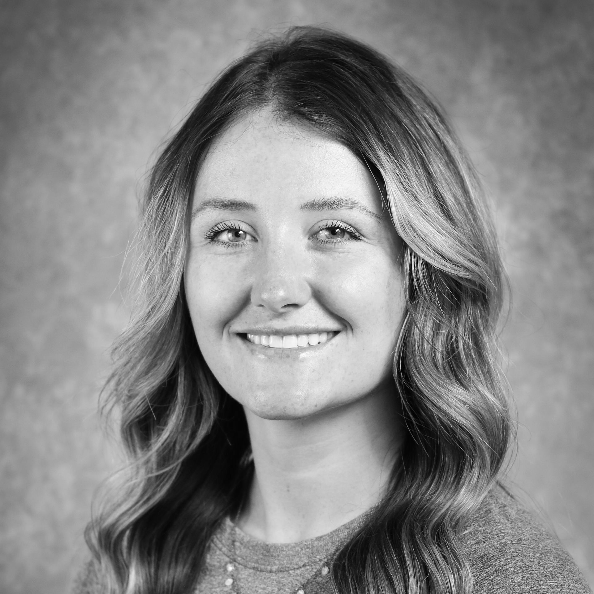 A woman in a purple shirt is smiling for the camera.