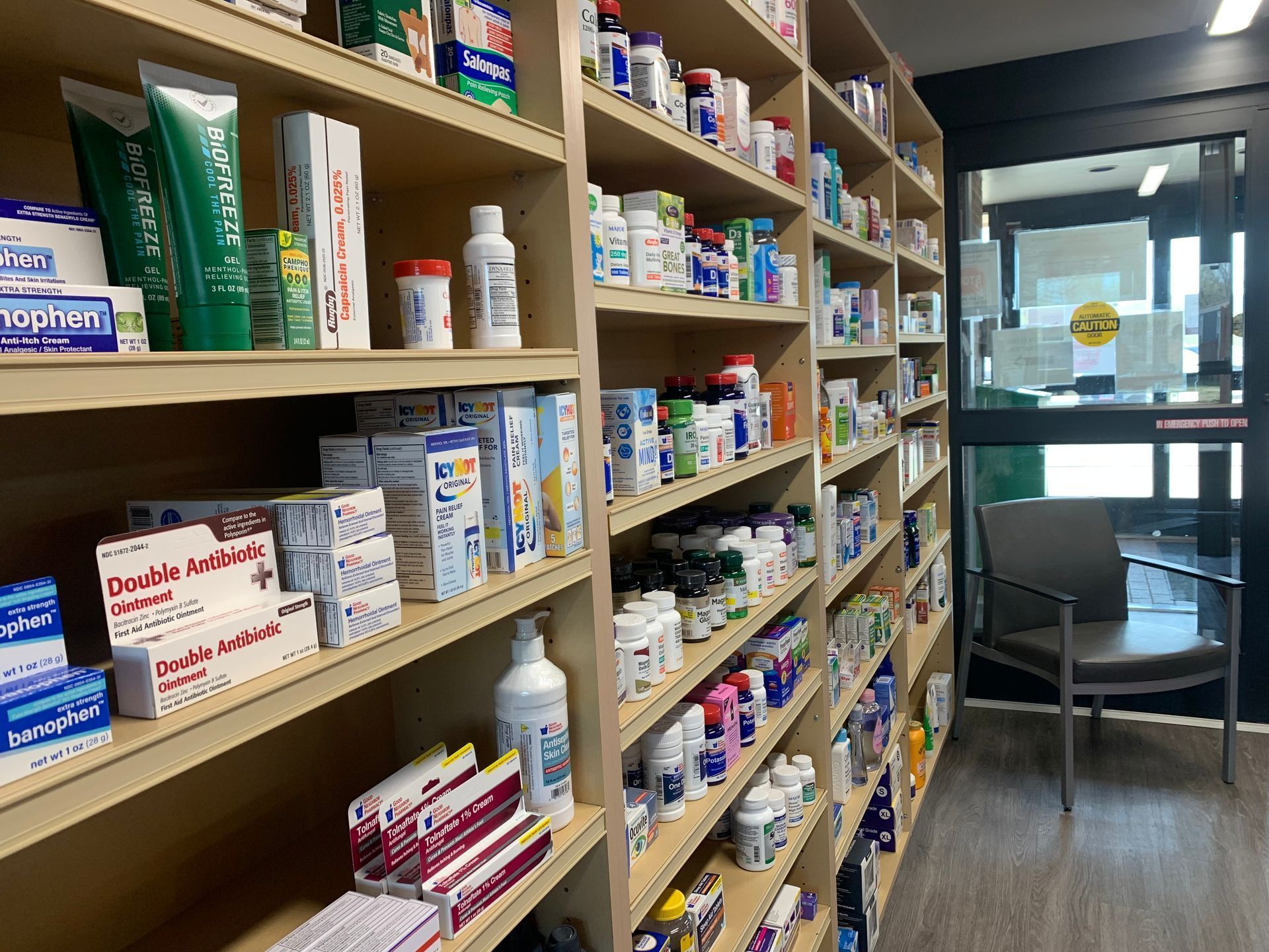 Hands selecting medicine boxes and blister packs from pharmacy shelves