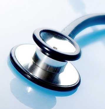 close-up of a silver stethoscope head with black rim, angled on a light blue surface