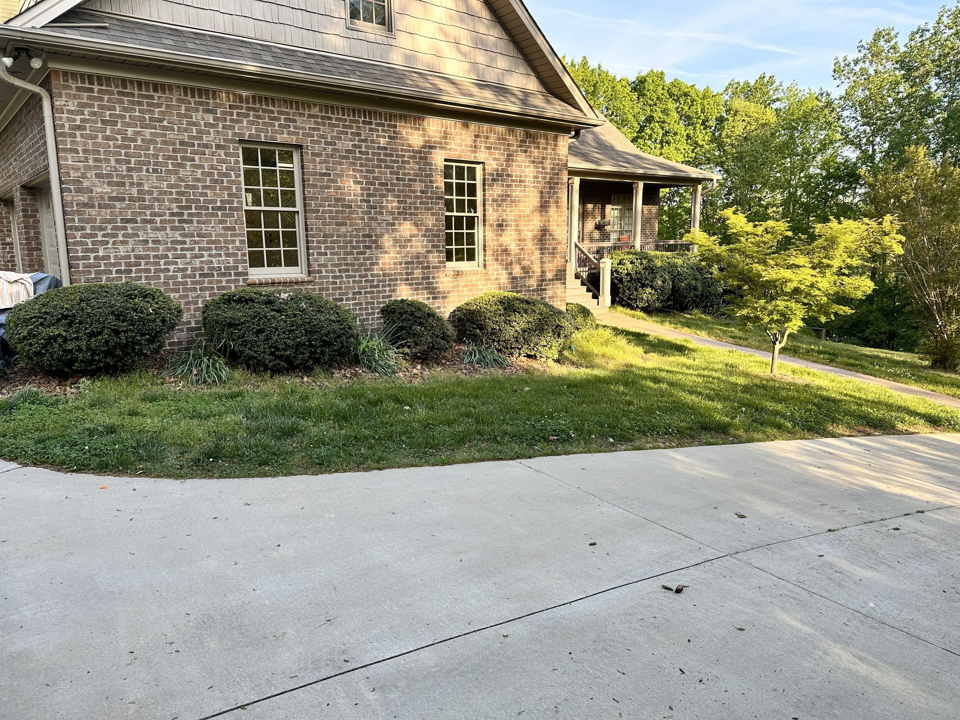 Brick house with porch and yard, sunny day.