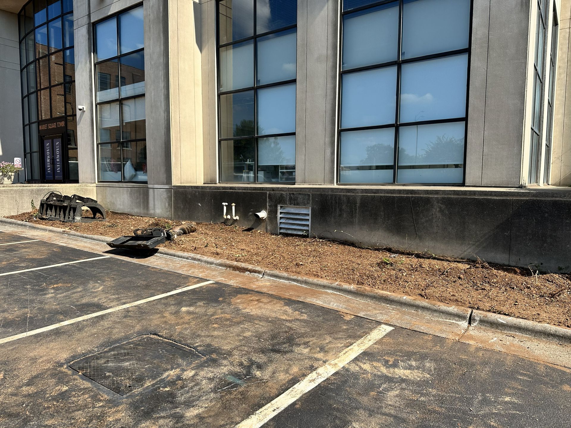 Building exterior with large windows, parking area, and landscaping with mulch.