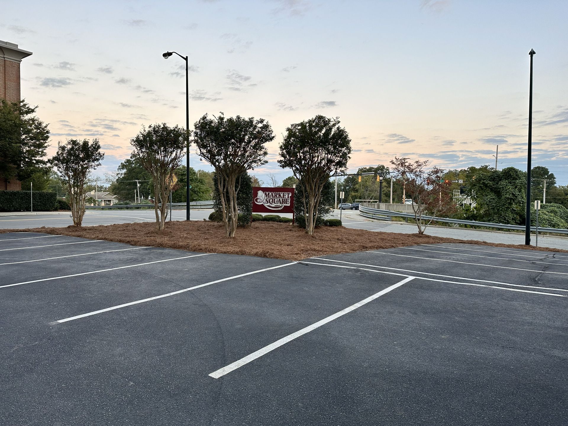 Parking lot with trees and a sign, under a cloudy sky.