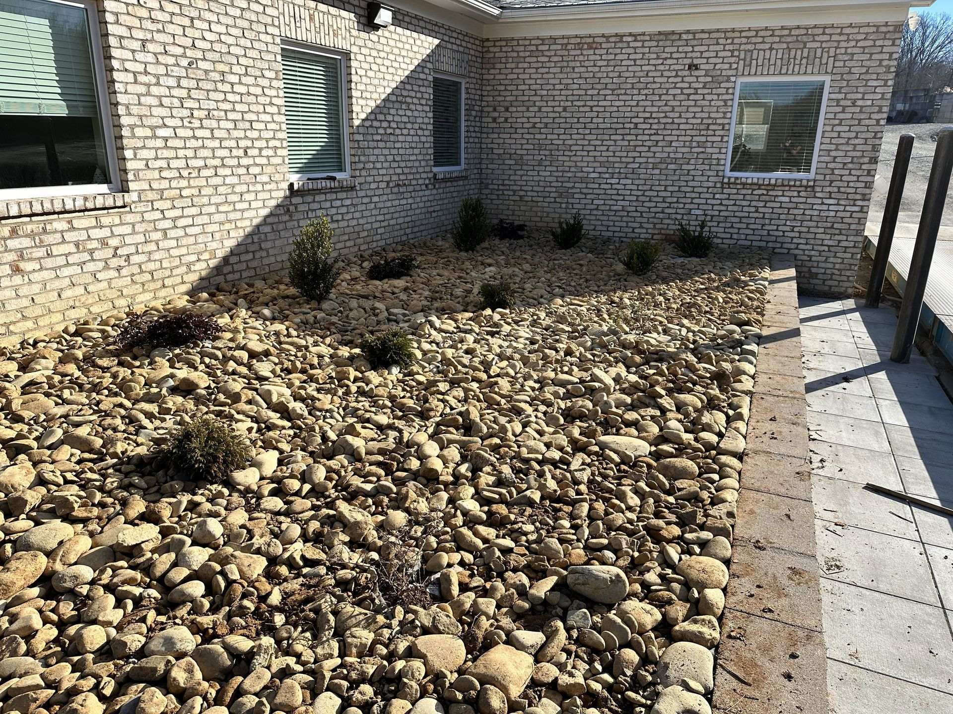 Exterior of a house with a rock bed and small bushes along the wall.